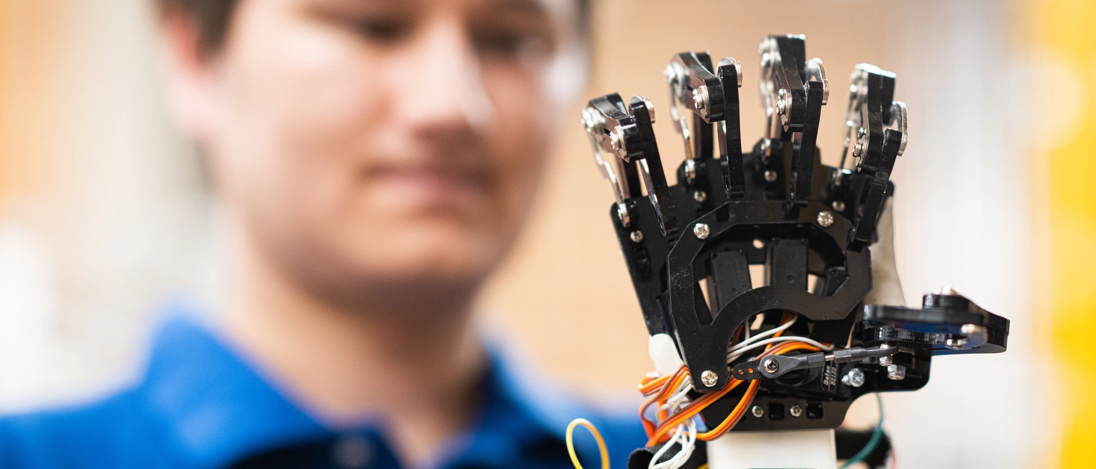 Student in engineering holds a robotic hand