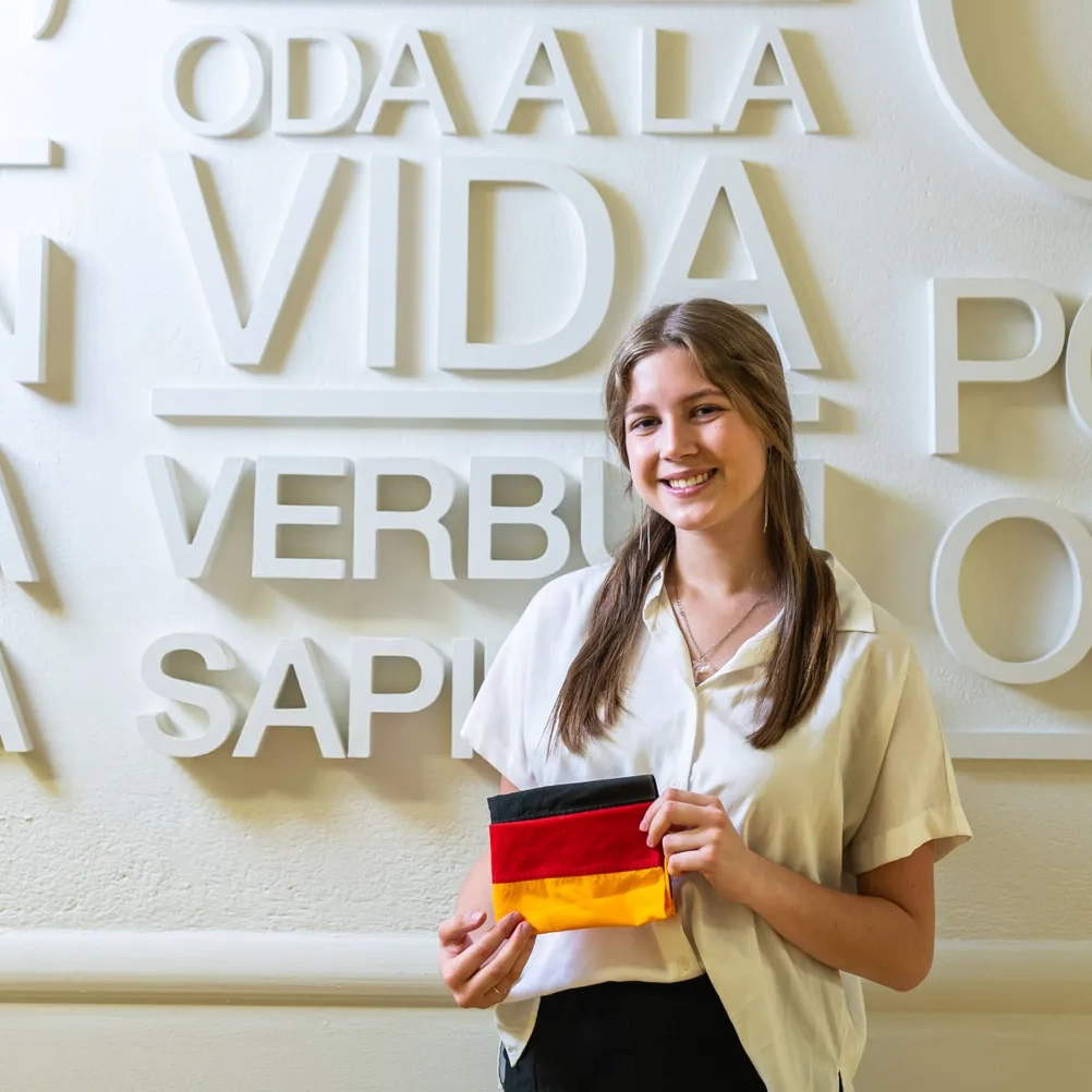 Zoë Lindner smiles in front of a wall displaying foreign languages