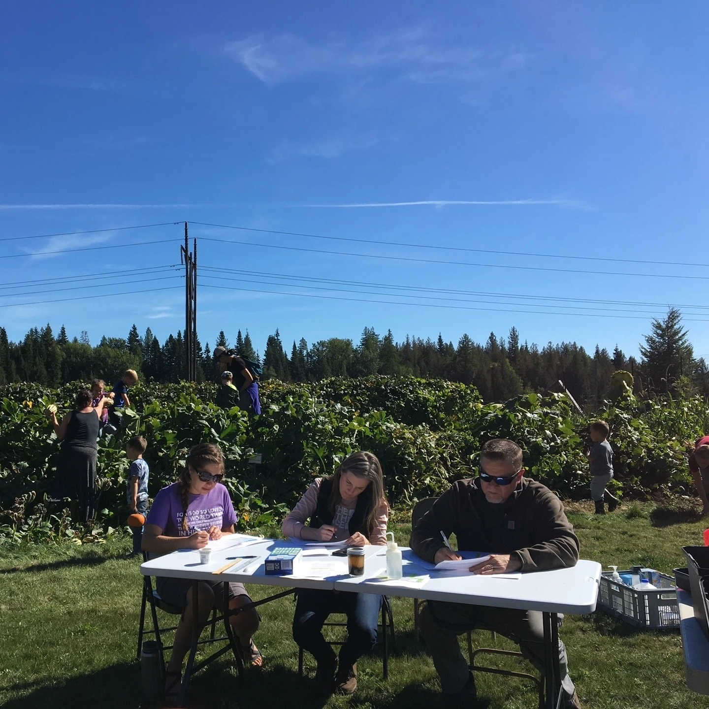 People sit and write at a table outside.