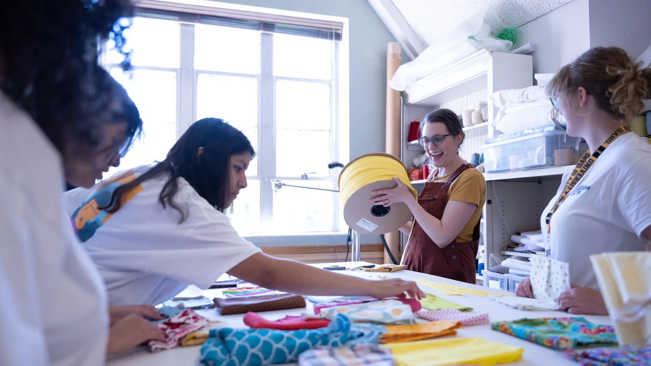 Five people stand around a table with piles of fabric.