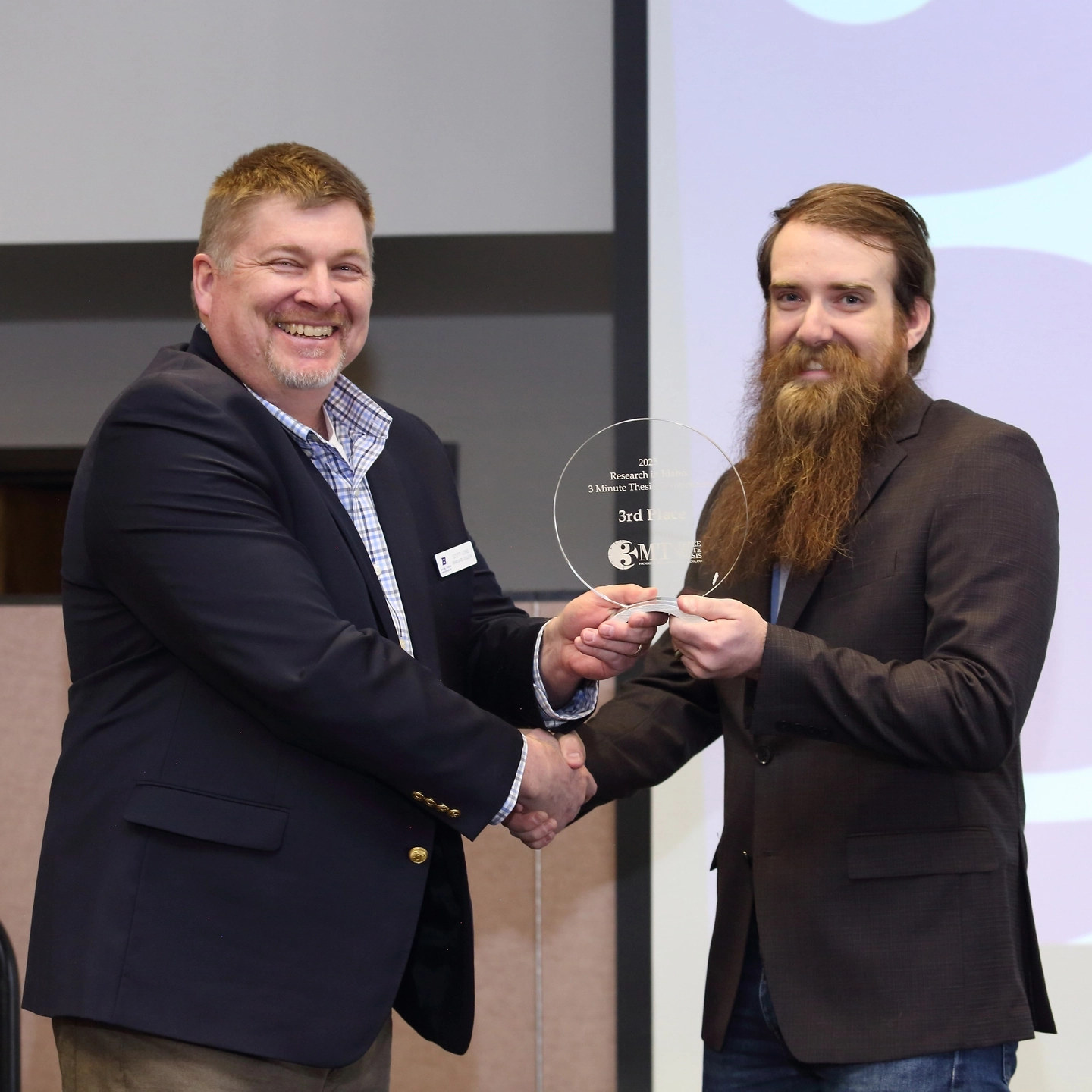 A man accepting an award from another man while standing on a stage