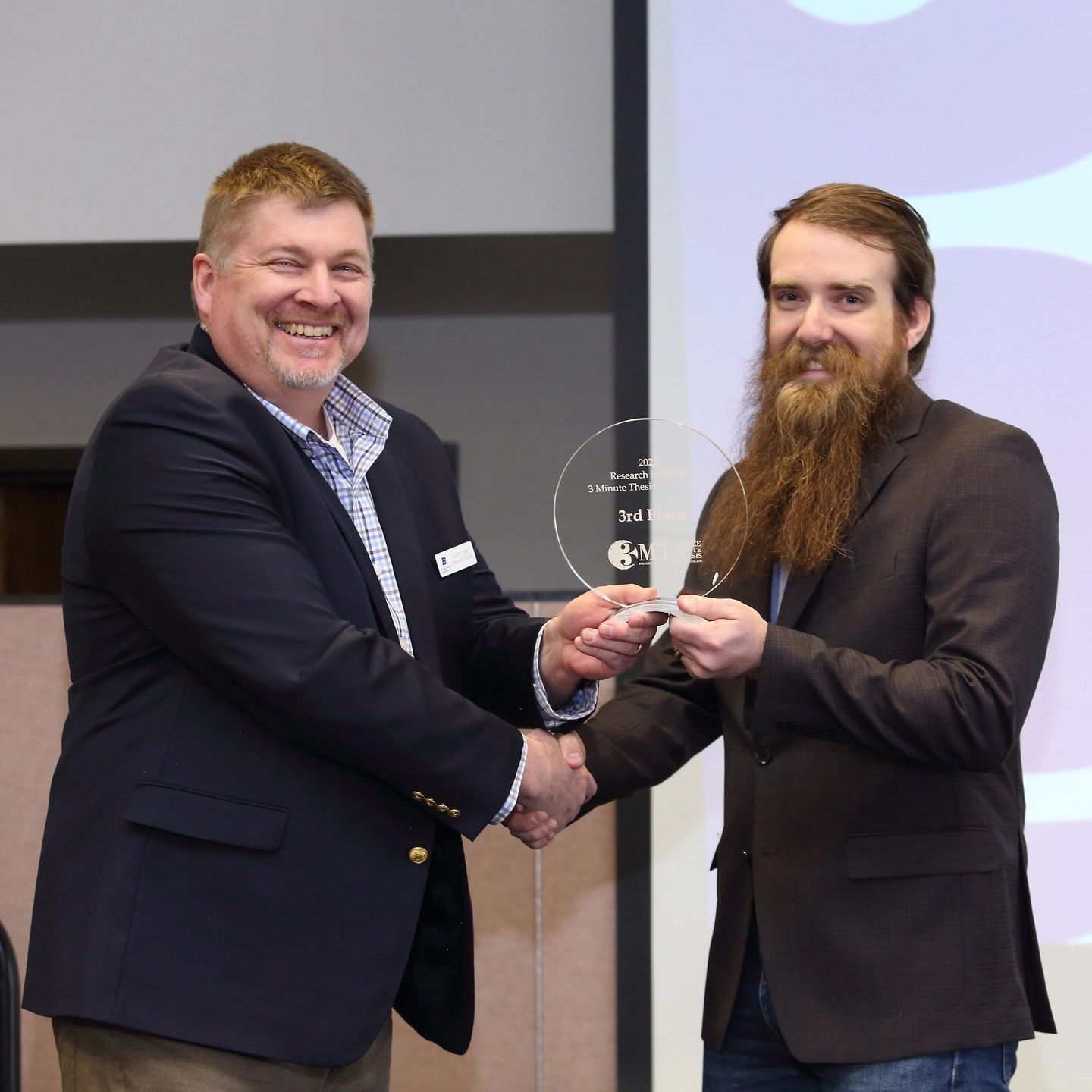 A man accepting an award from another man while standing on a stage