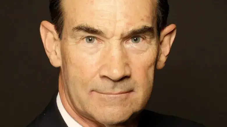 An older man looking into the camera wearing a suit