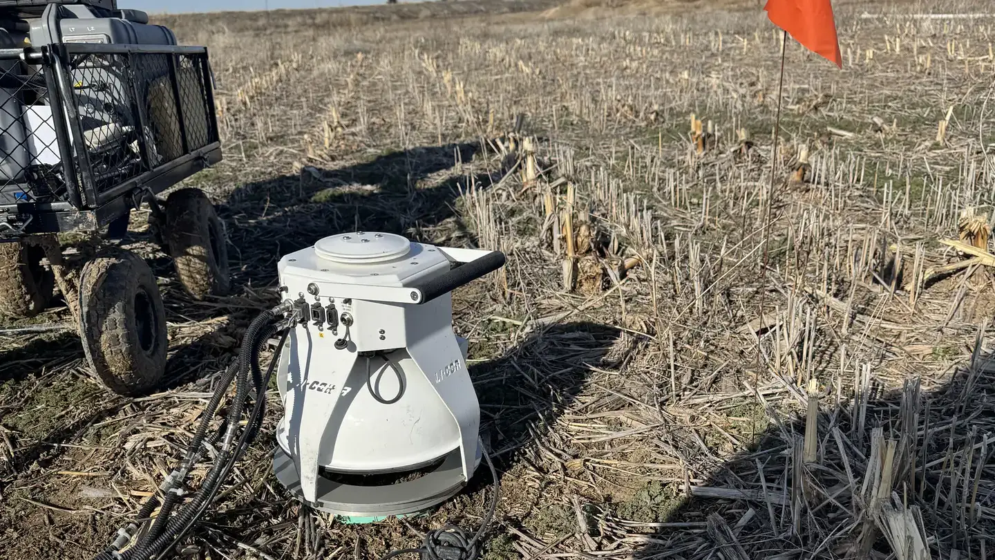 A chamber used to measure gas emissions is set up amid a field.