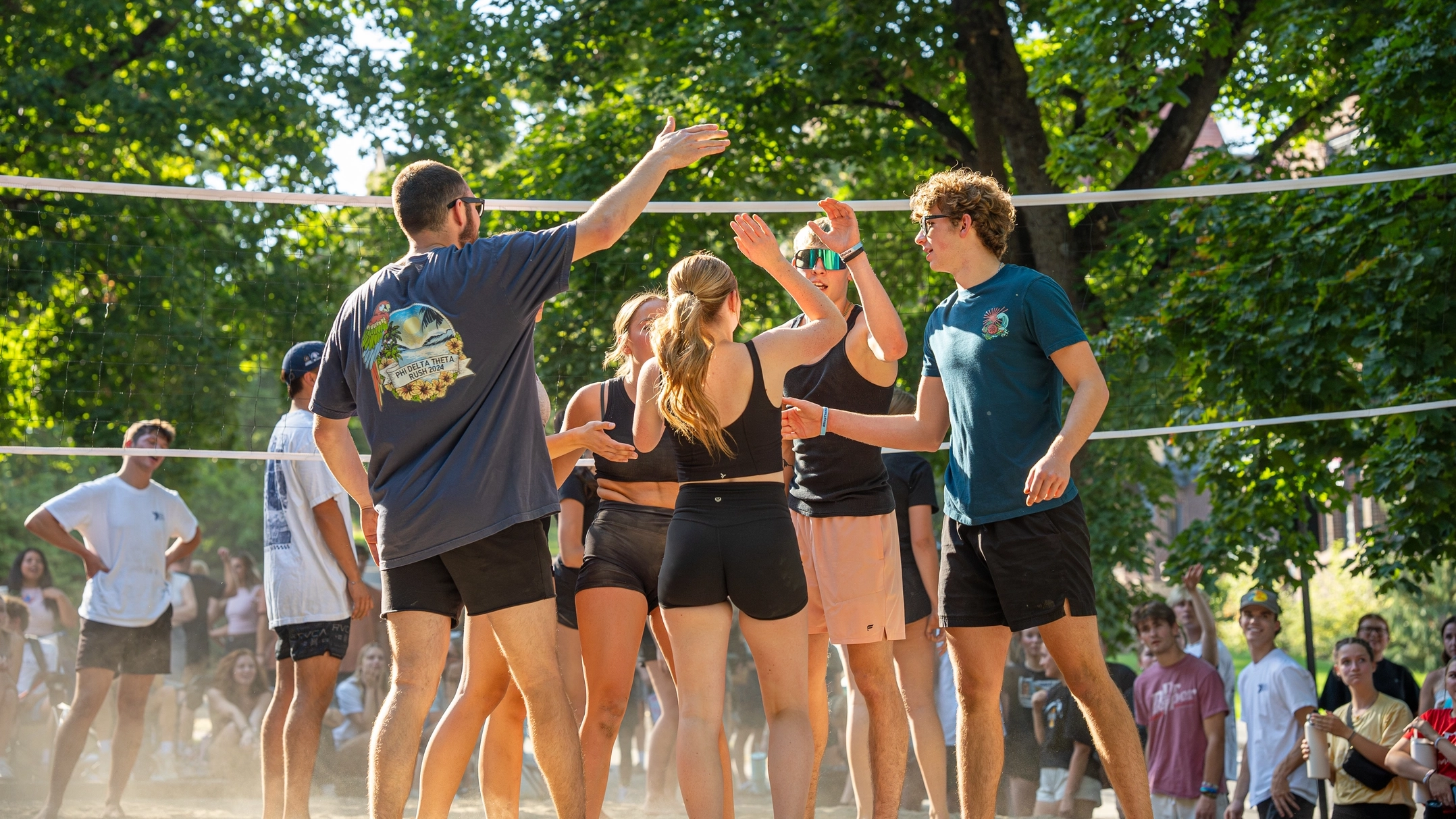 Teammates exchange high fives by a volleyball net.