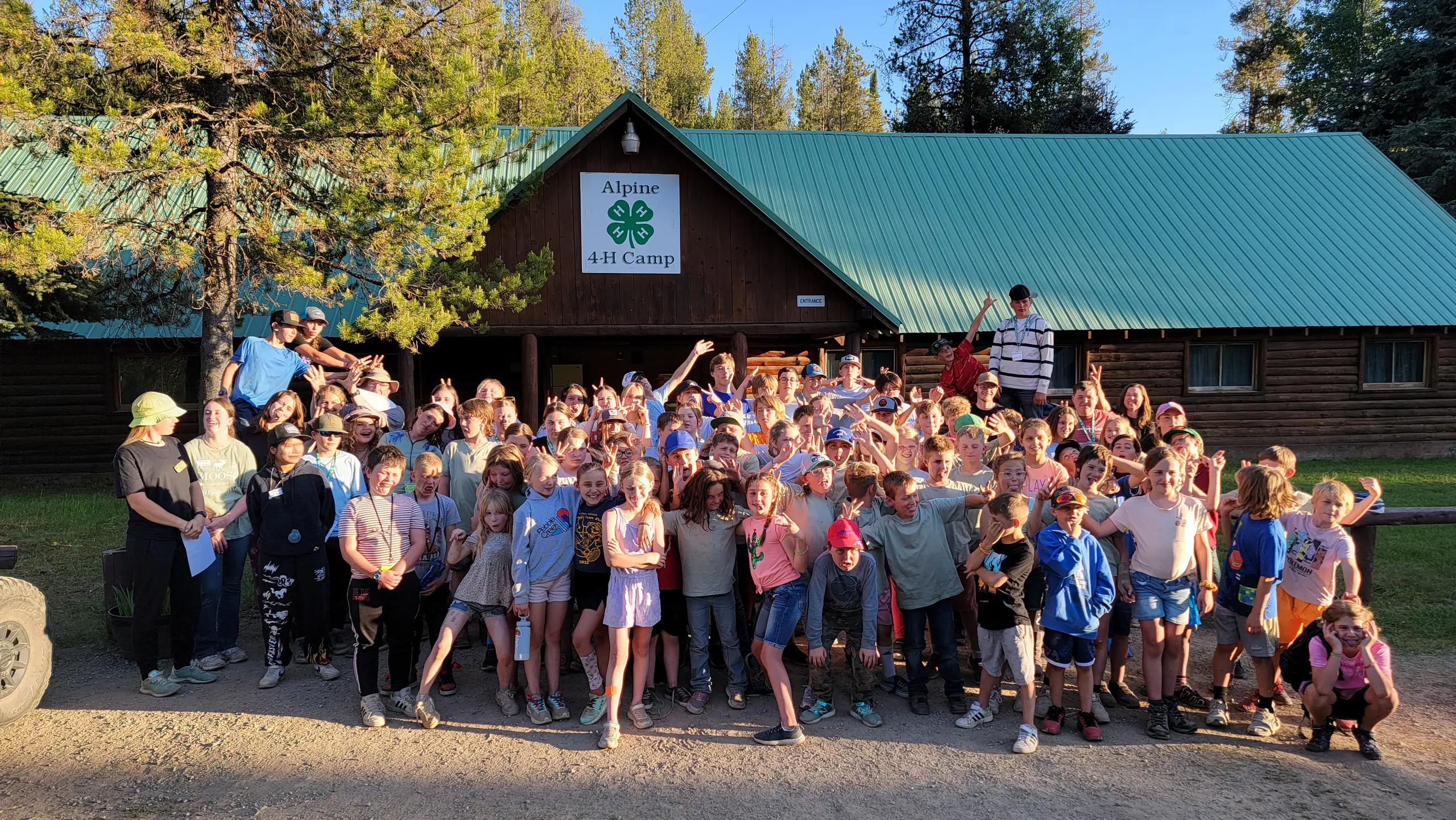 group poses outside cabin with 4-H clover