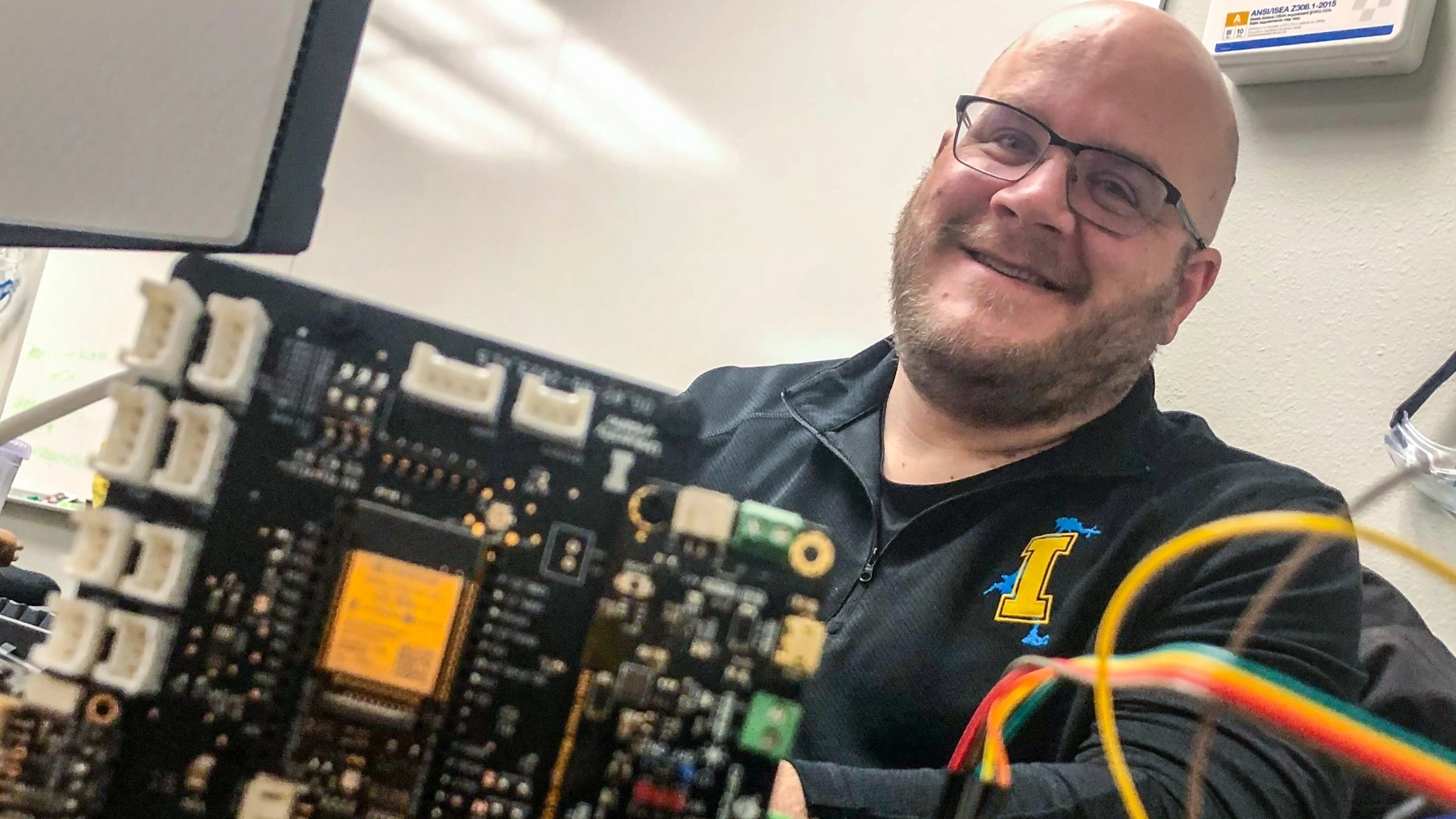 Kevin Wing, with circuit boards and wires in the foreground