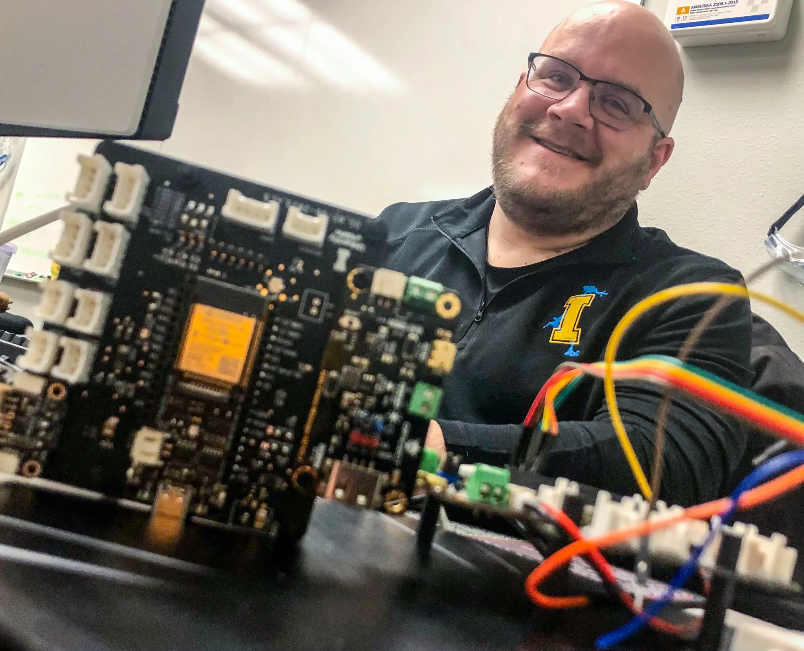 Kevin Wing, with circuit boards and wires in the foreground