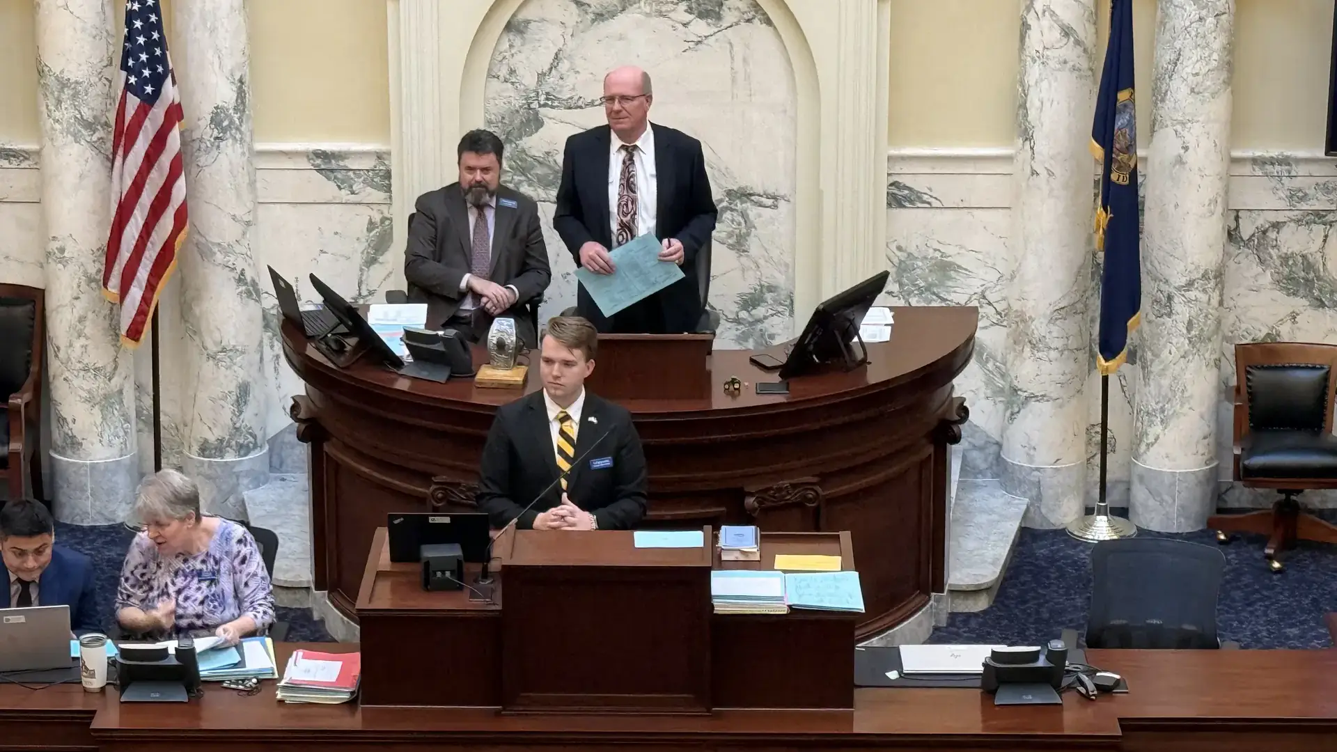 A man stands at a podium on the floor of the Idaho House of Representatives.