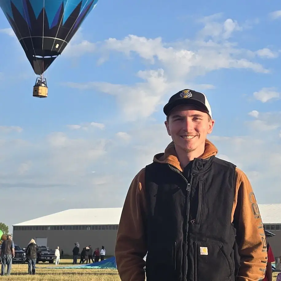 Cameron Ball with a hot air balloon floating behind him.