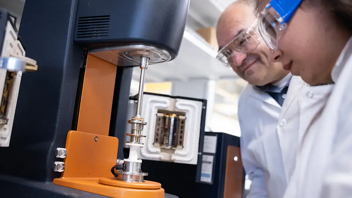 A man and a woman stare at a machine.
