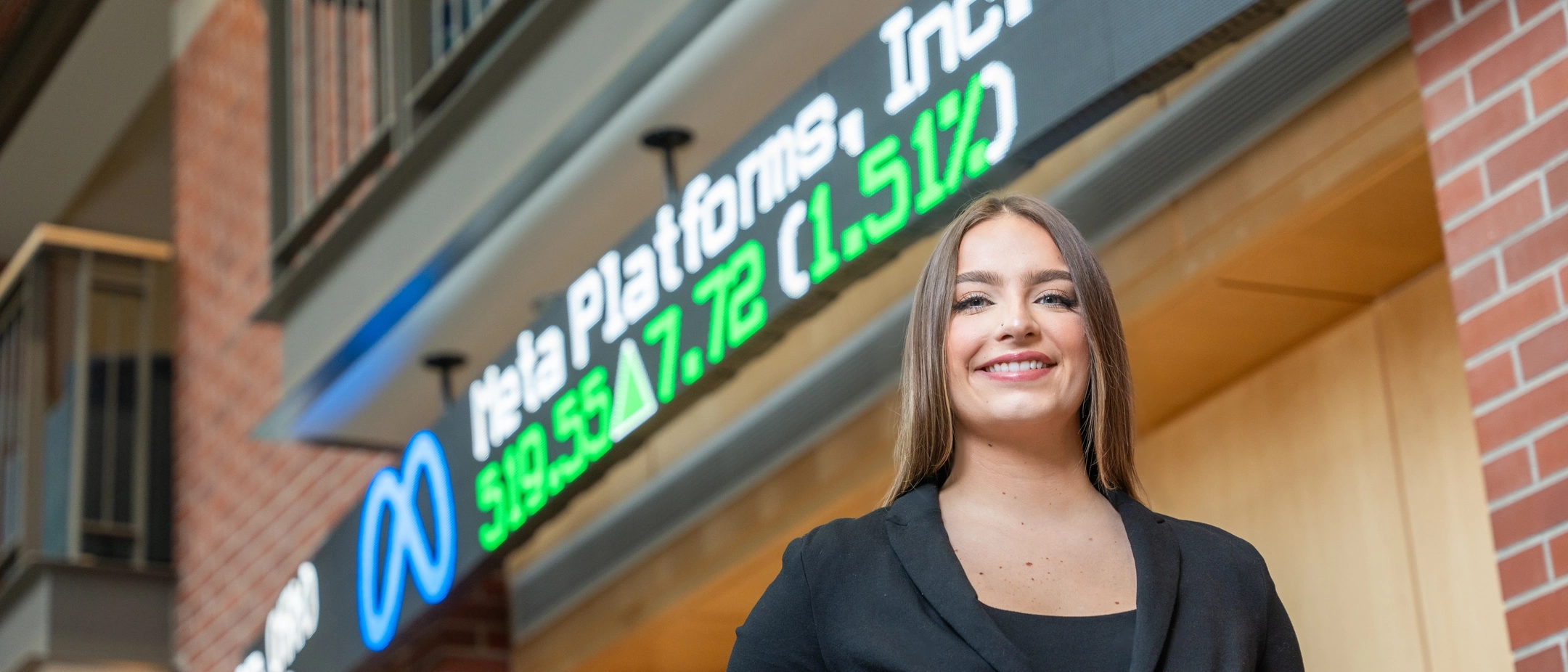 person standing in nice business casual near a business scrolling display