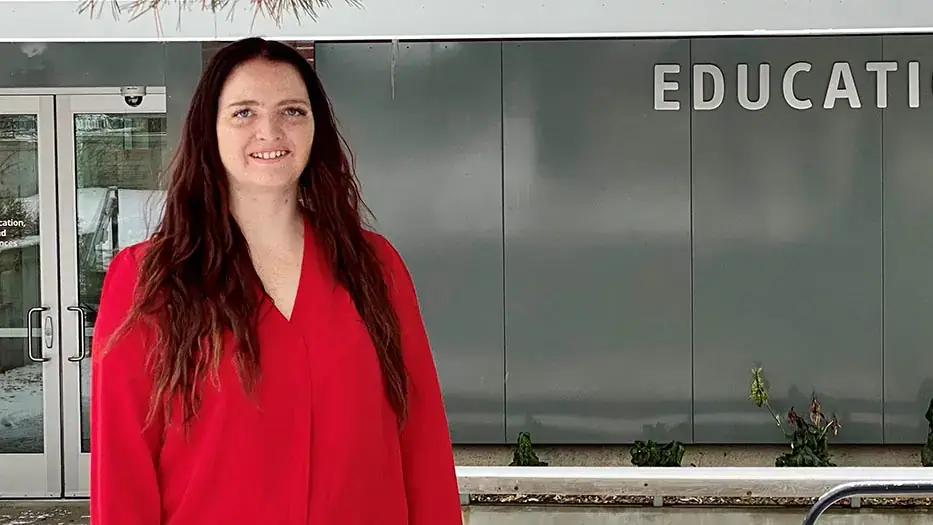 woman smiles outside of the education building