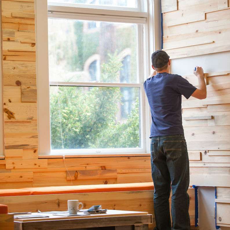 A design-build student works on the wood paneling in the Art and Architecture South welcome area