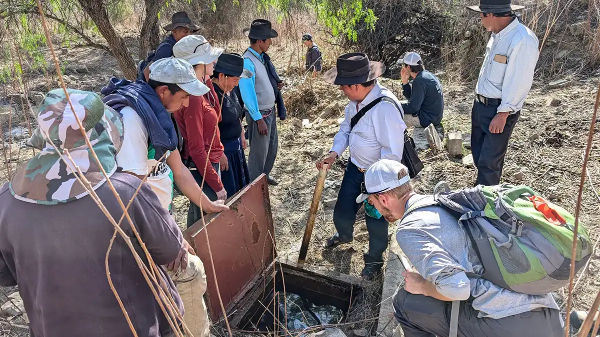 A group stand around the entrance to an irrigation system.