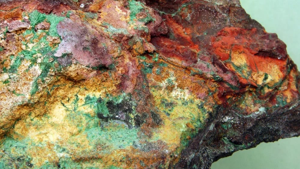 A sample of porphyry copper showing green, yellow, orange, red and dark red colors on its surface