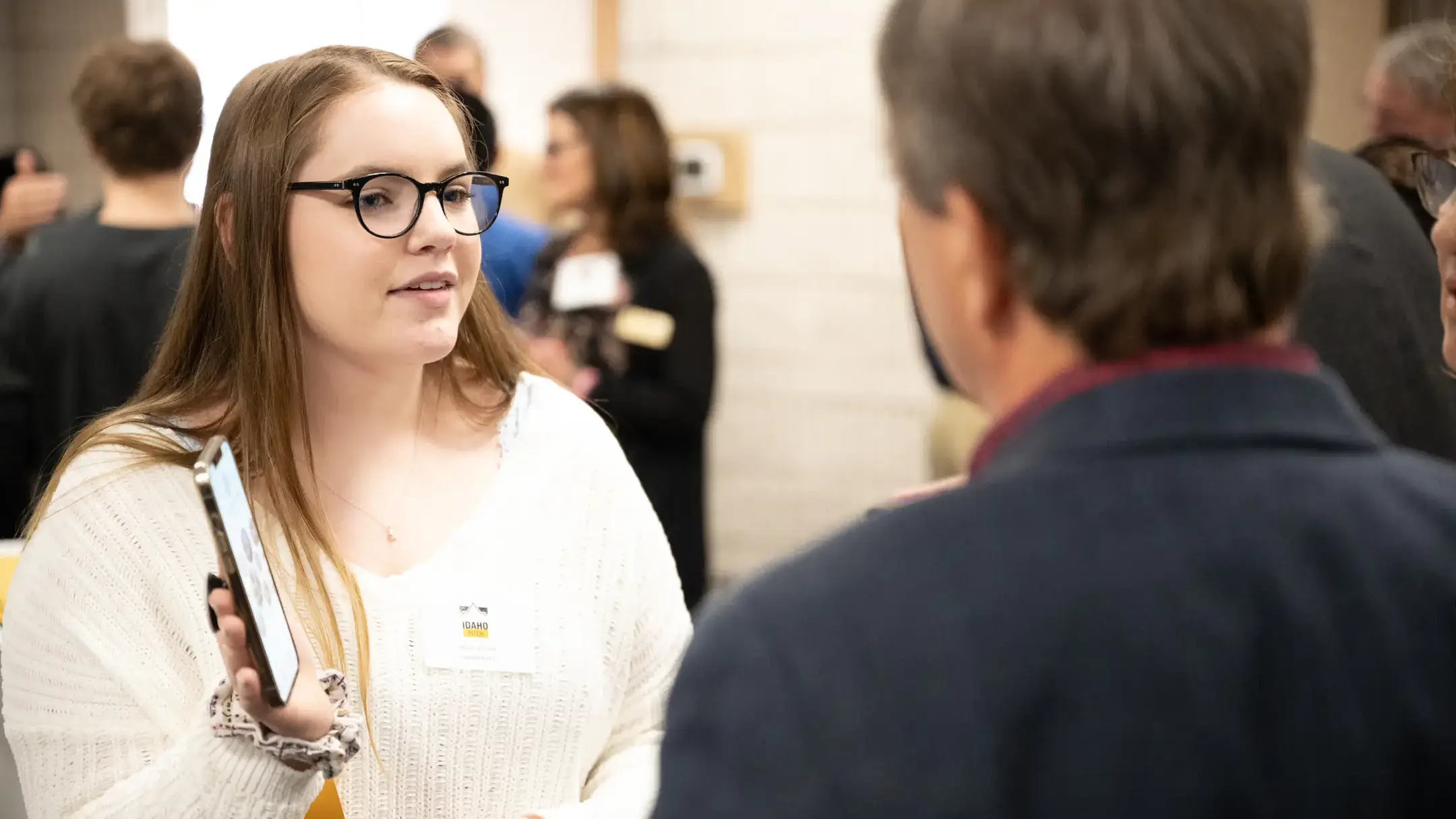 A student holding up their cellphone to pitch their unique product to a potential investor.