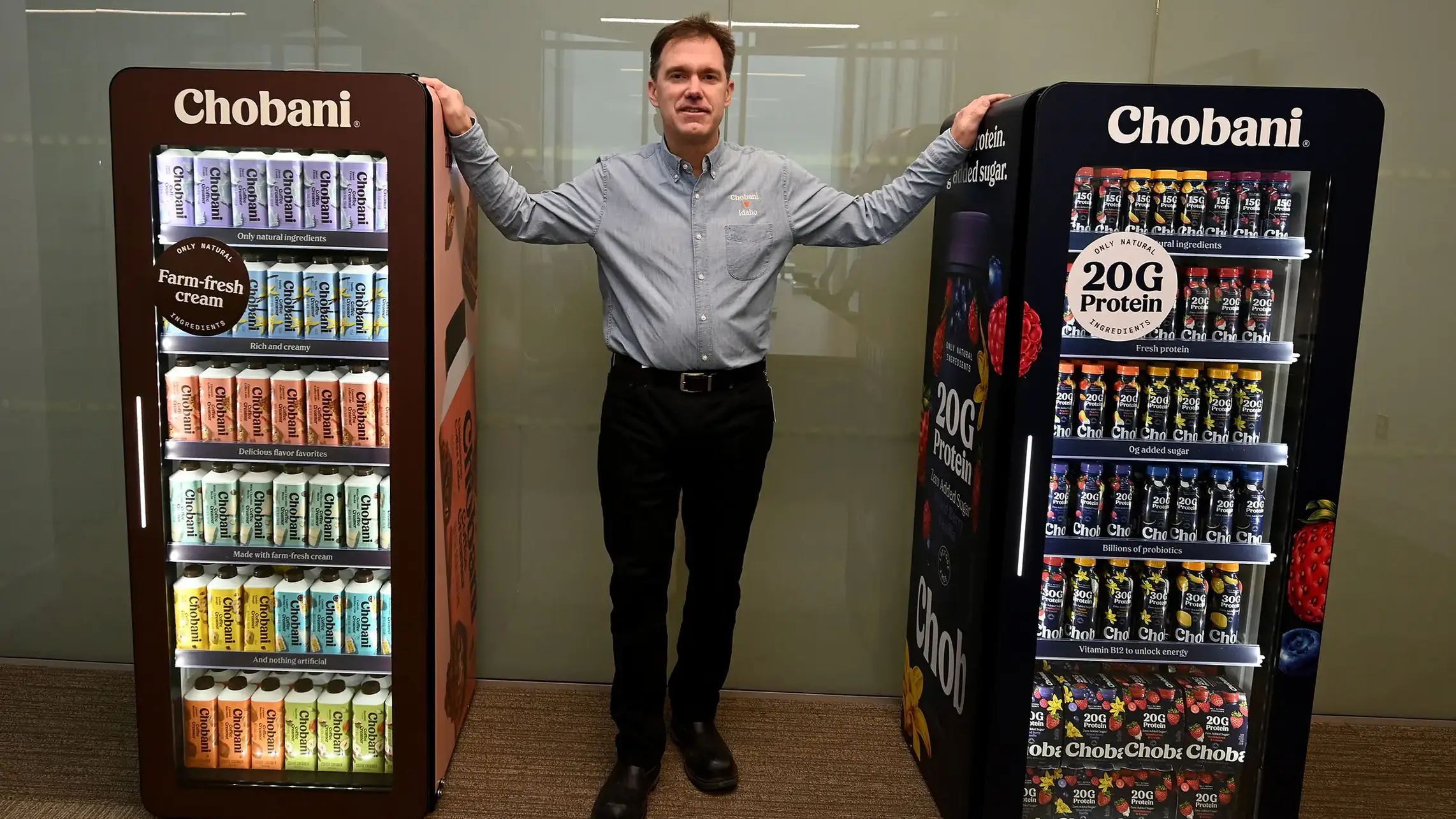 Peter Krell rests his arms on refrigerators filled with yogurt on either side of him.