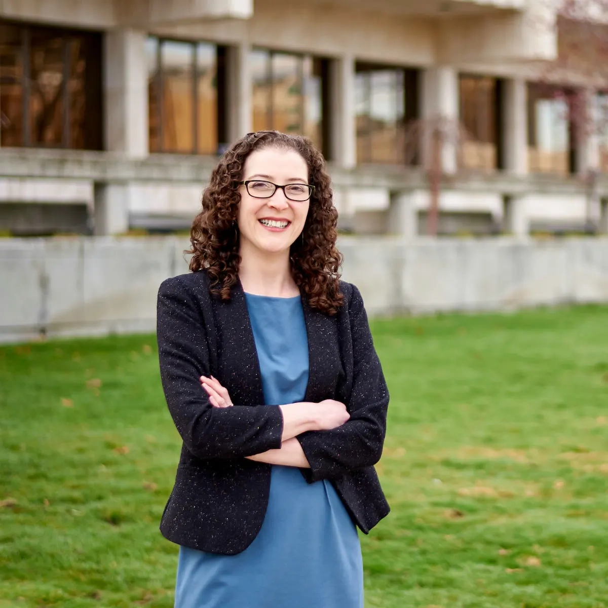 A woman smiling in front of a building in a lawn