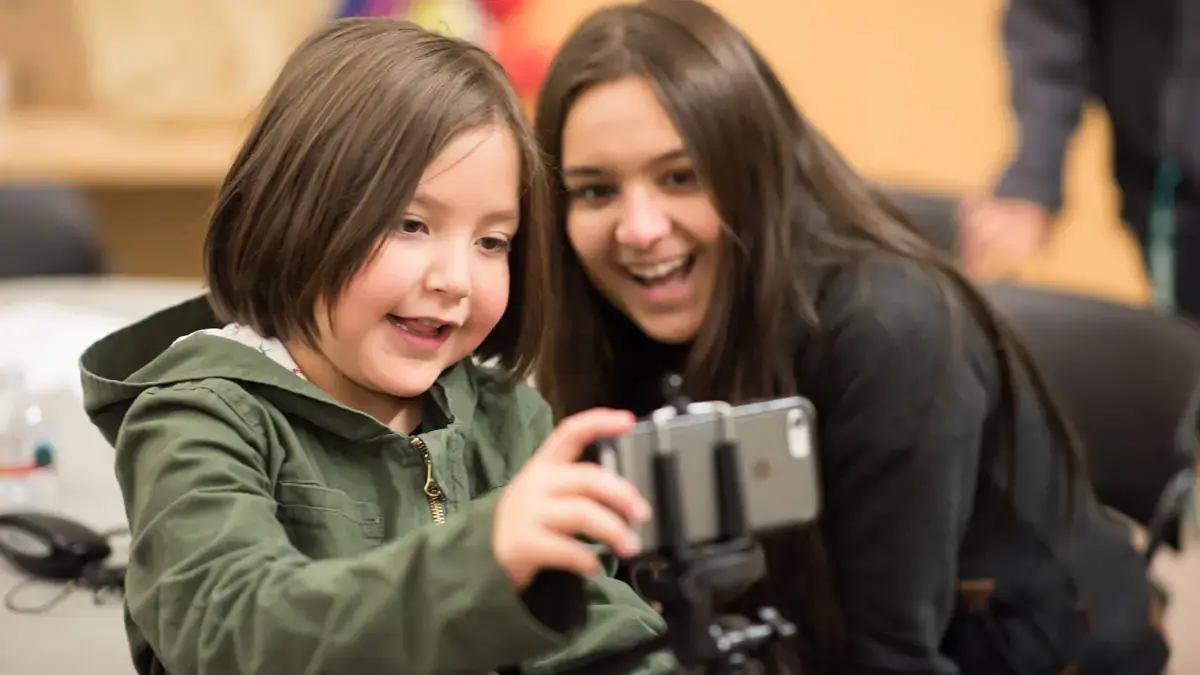 Two young students look at a phone.