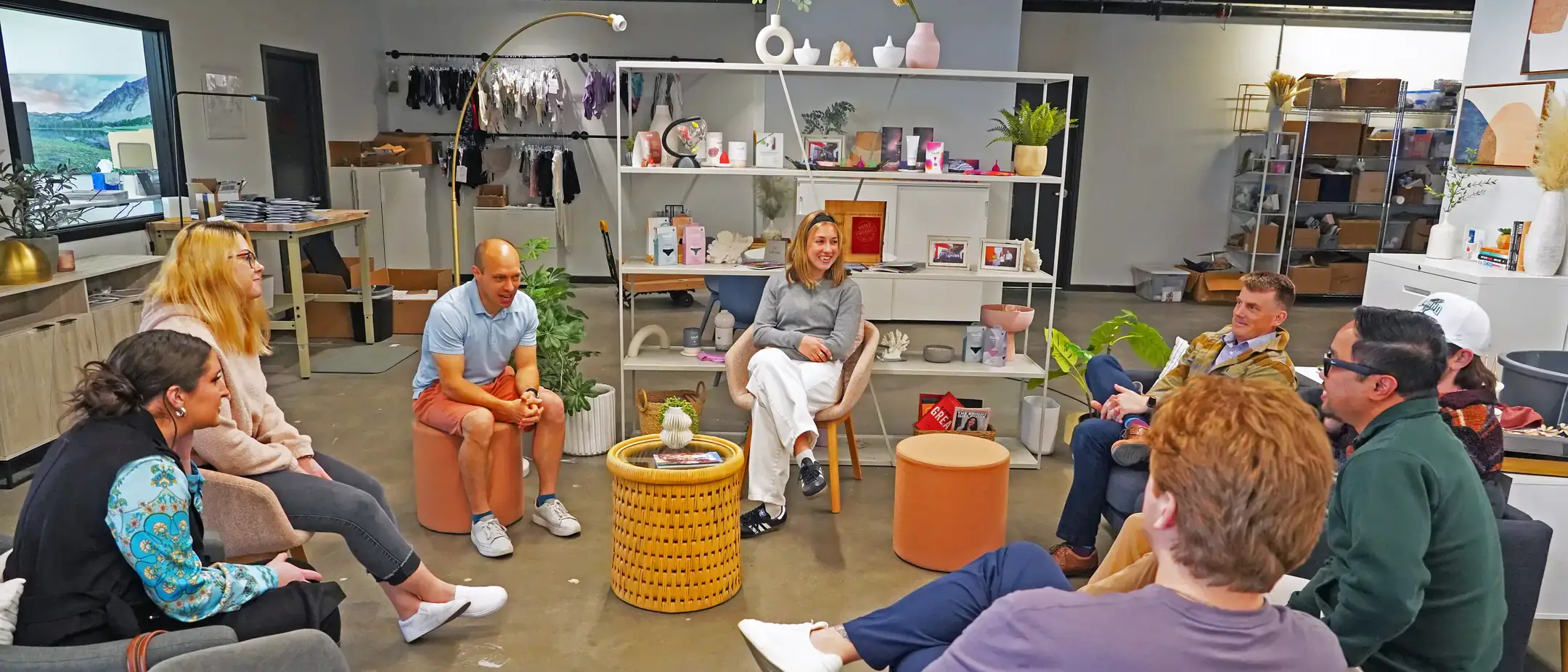 People sitting in a circle during a discussion in an office space furnished with shelves and chairs.