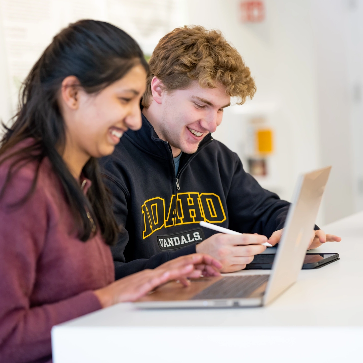 Girl and boy smiling and looking at laptops