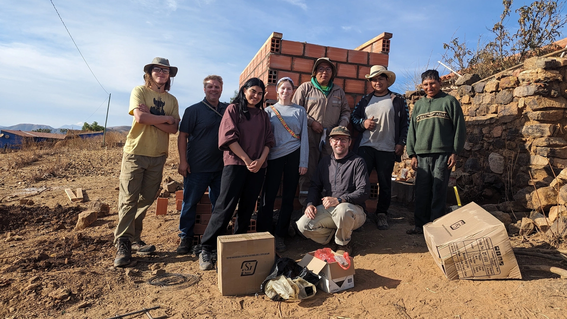 Students pose in front of a brick structure