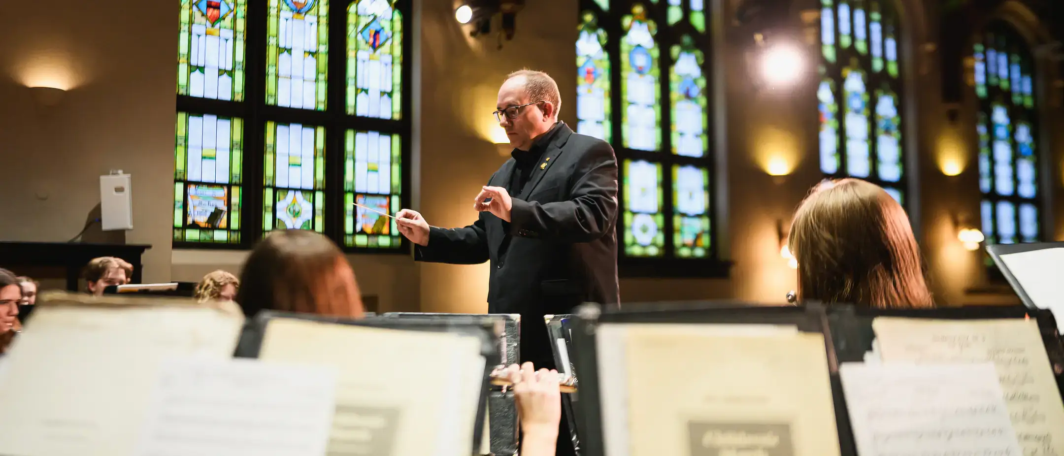 A man orchestrating a band in the middle of a performance.