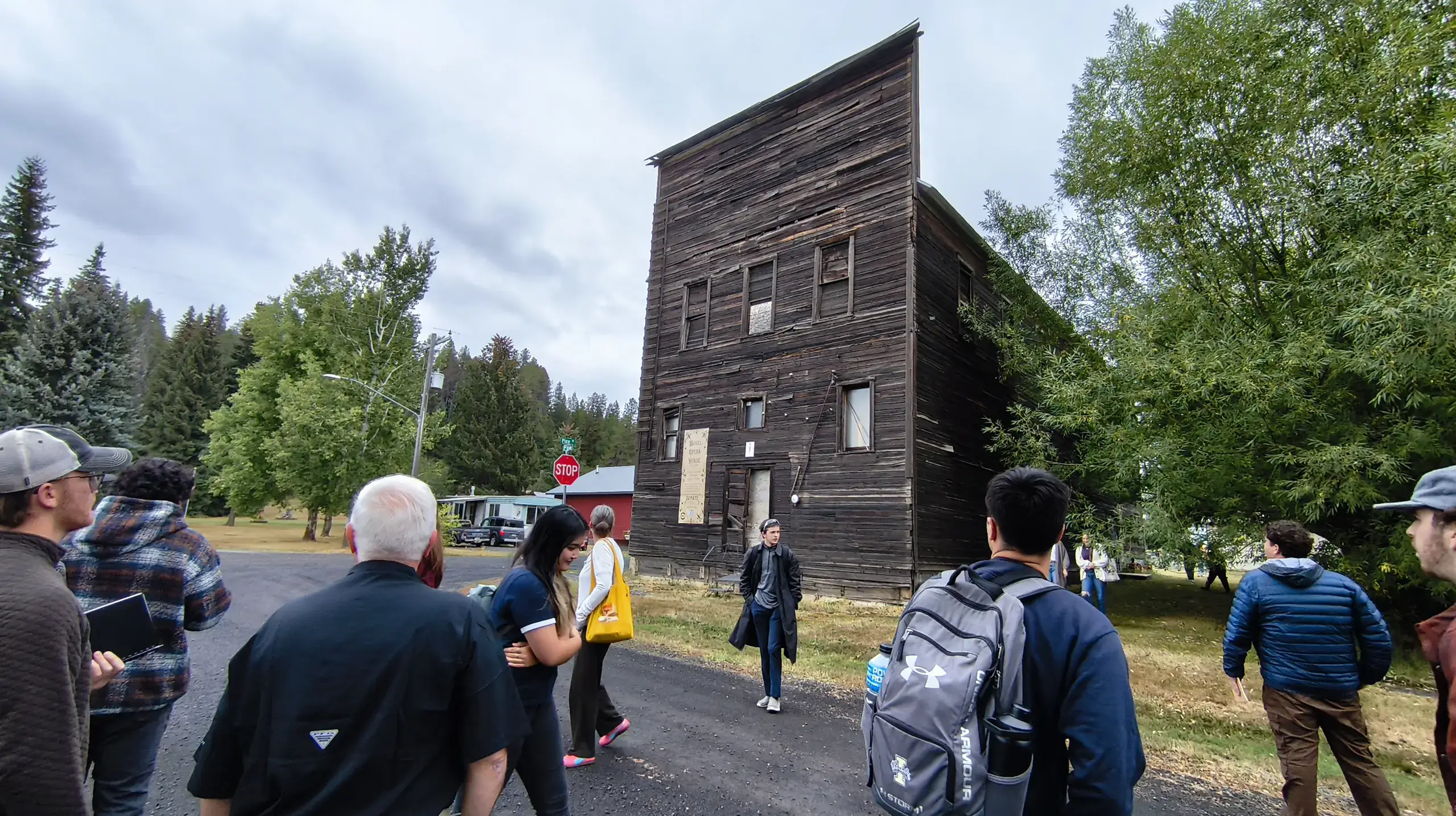 The Bovill Opera House, a two-story and narrow wood building, with men and women standing around it.