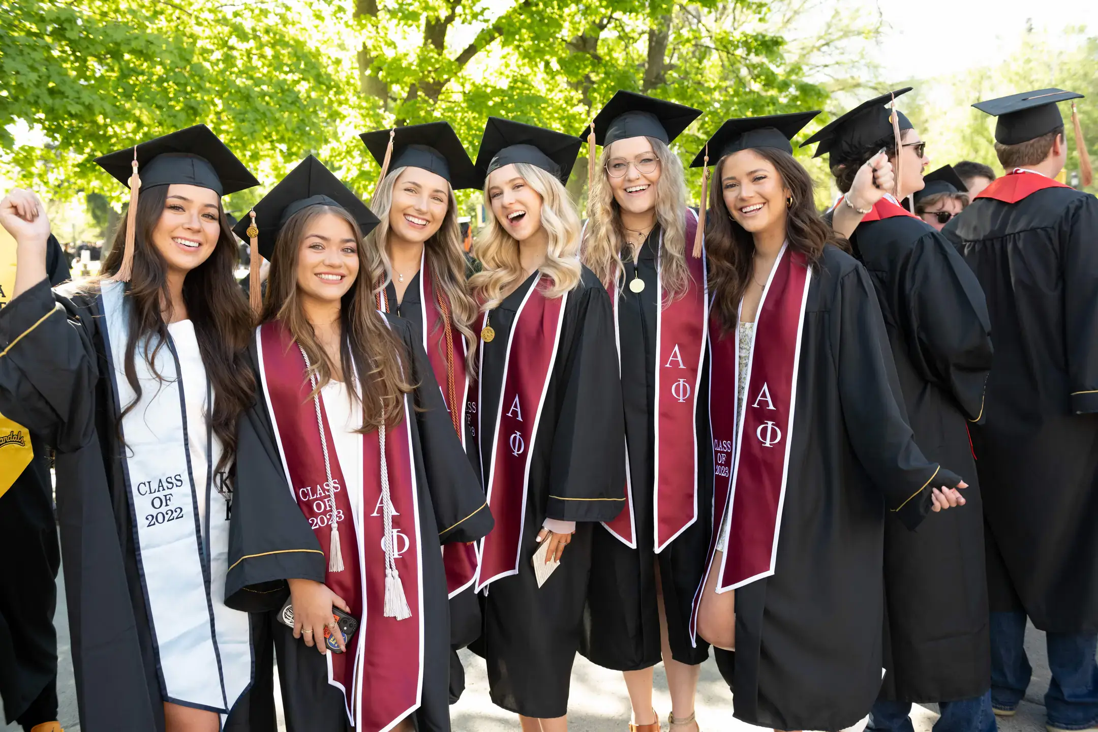 Greek life students posing in their cap and gown on graduation day.