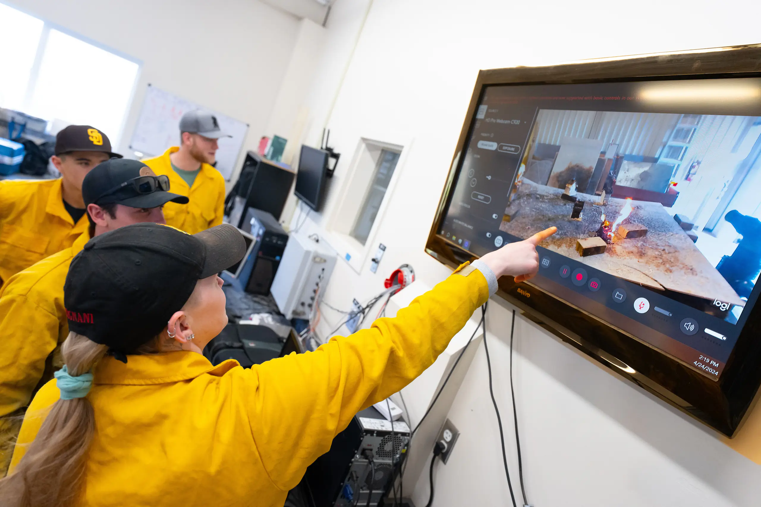 Group of students analyzing wildfire simulation on a large screen in a classroom setting. 