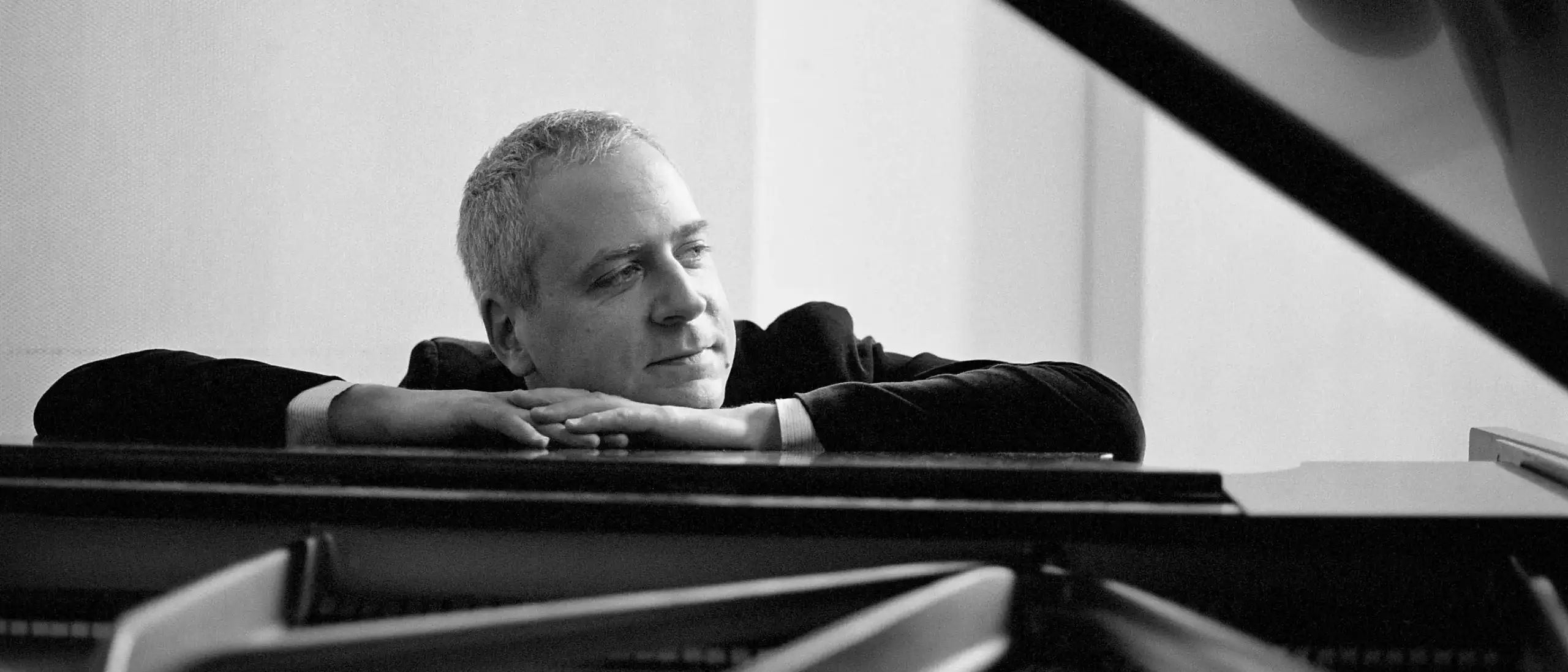 A man resting his head and arms on a piano.