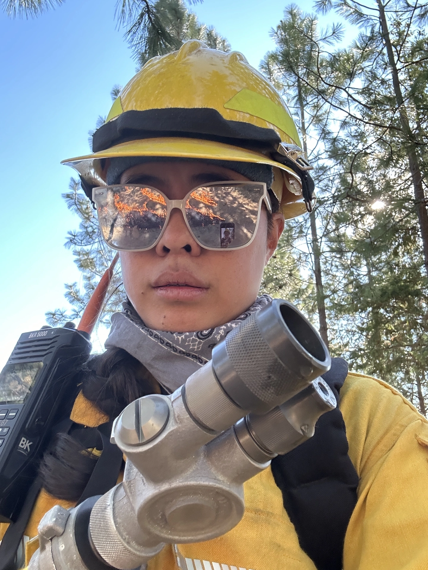 Selfie of Jennifer in protective gear, holding a fire hose.