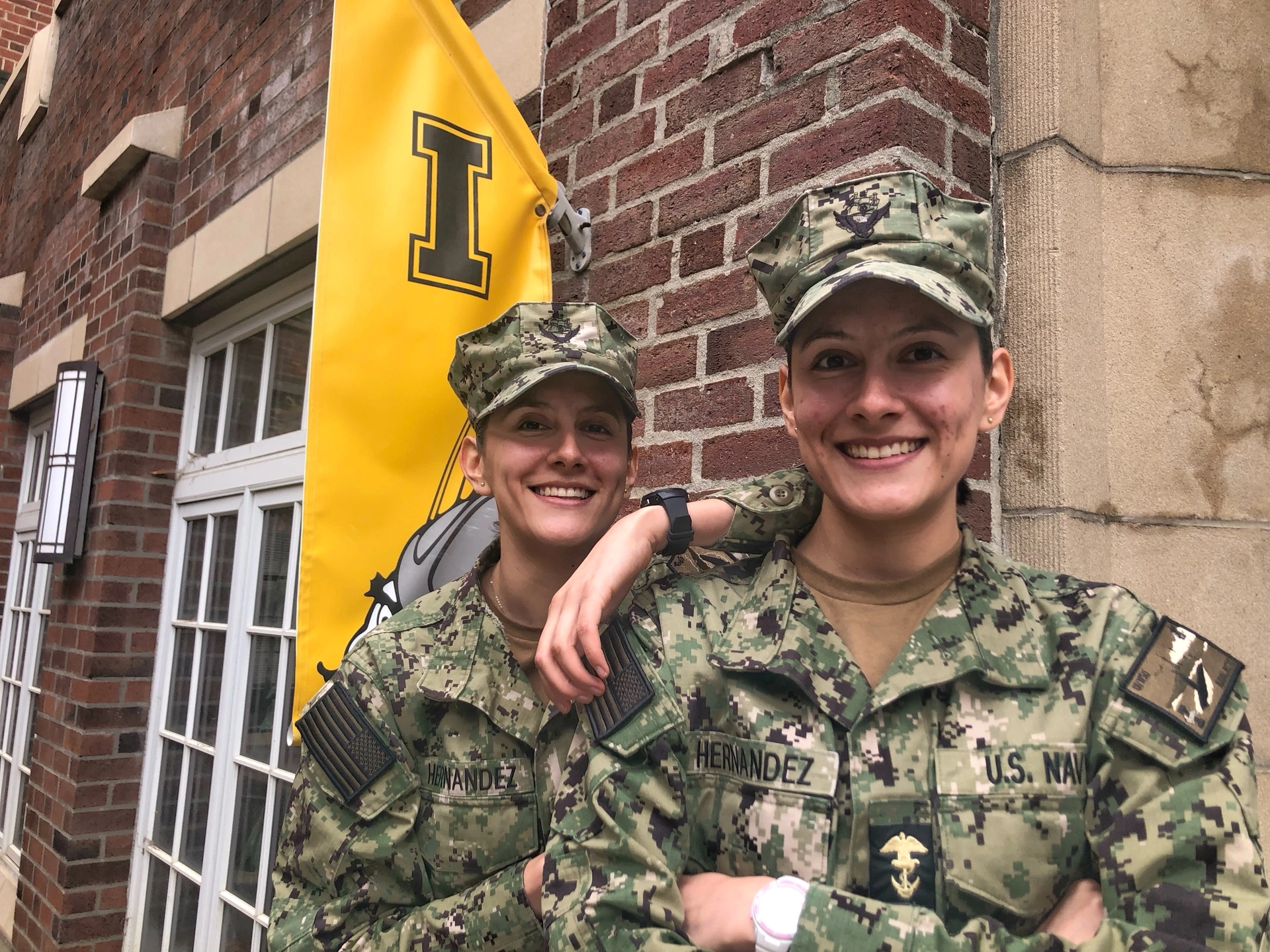Two women in uniform stand in front of the Alumni Relations office.