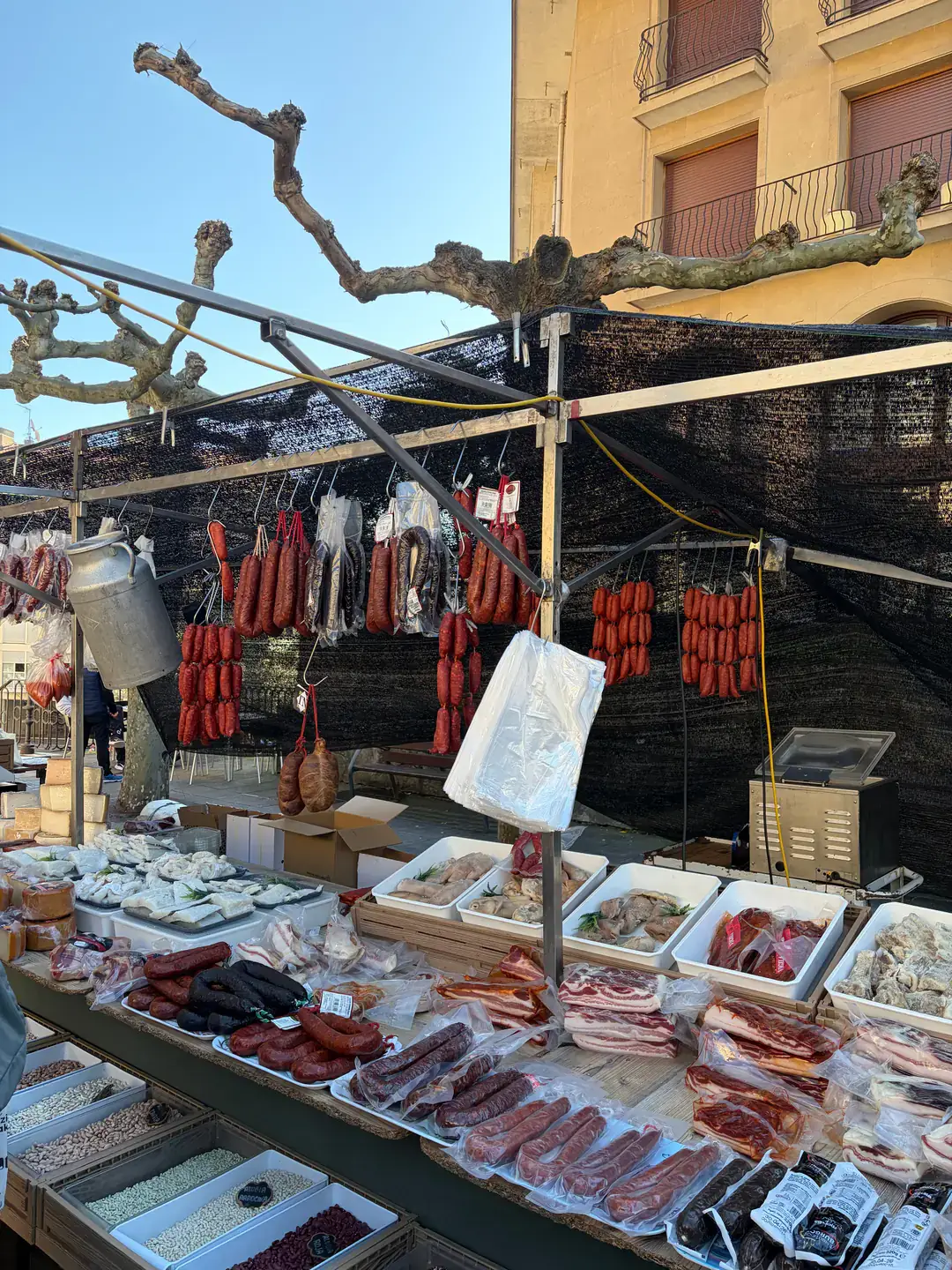 Cured meat and other agricultural products are sold at a farmer’s market booth.