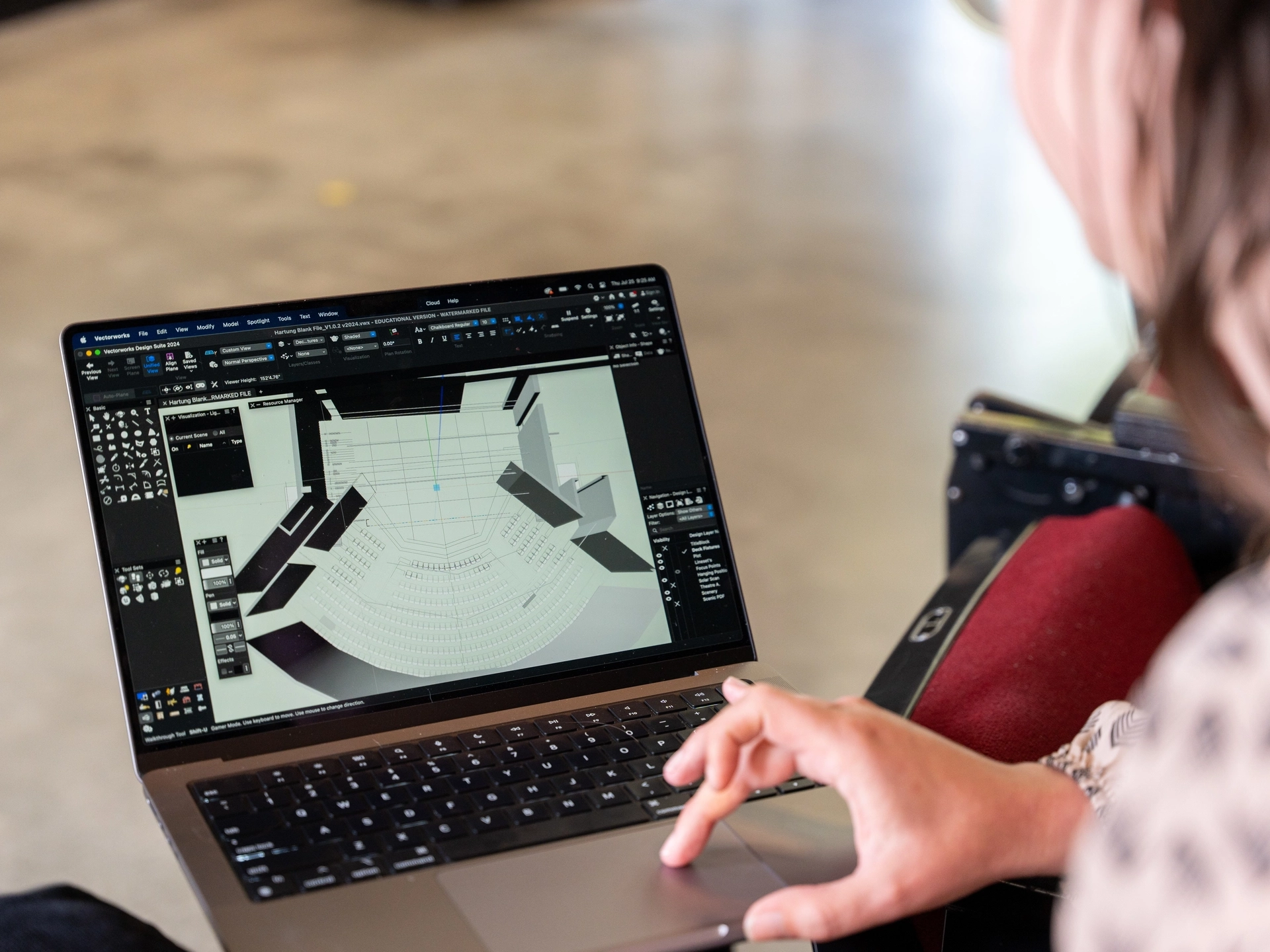 Woman in background working on computer with screen showing a theater