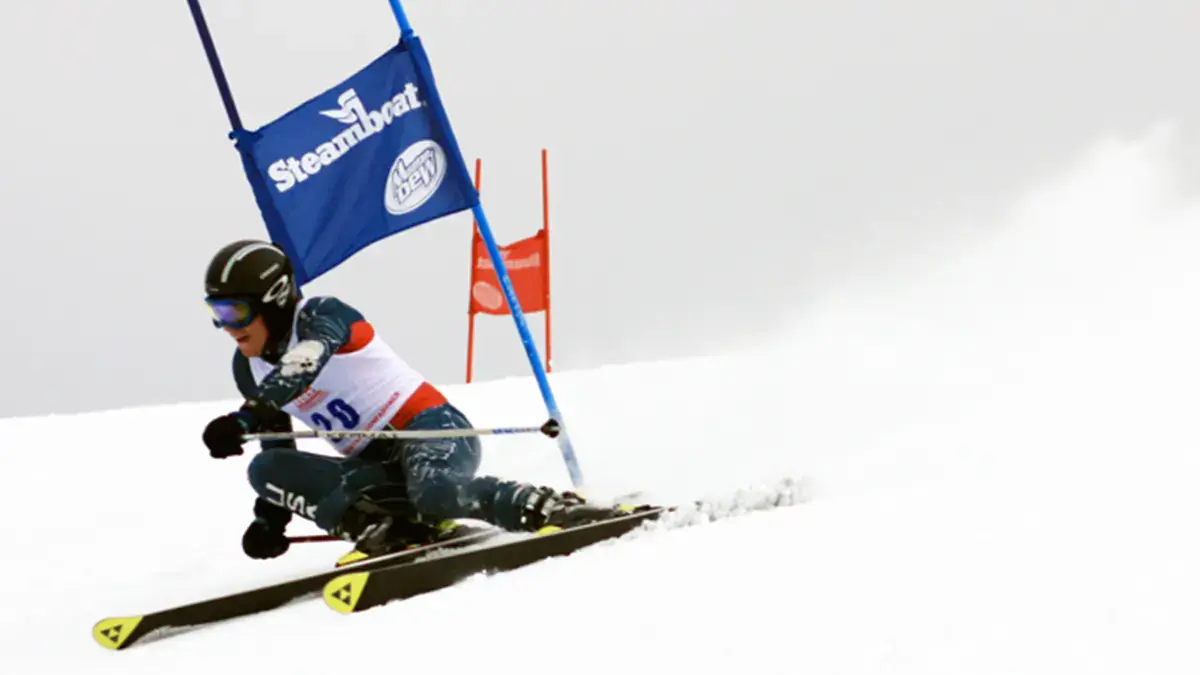 A person skiing past competition sponsor flag on mountain.