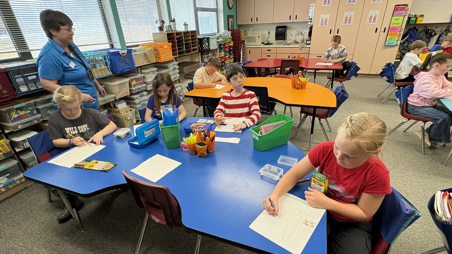 Children draw pictures at a table at an elementary school.