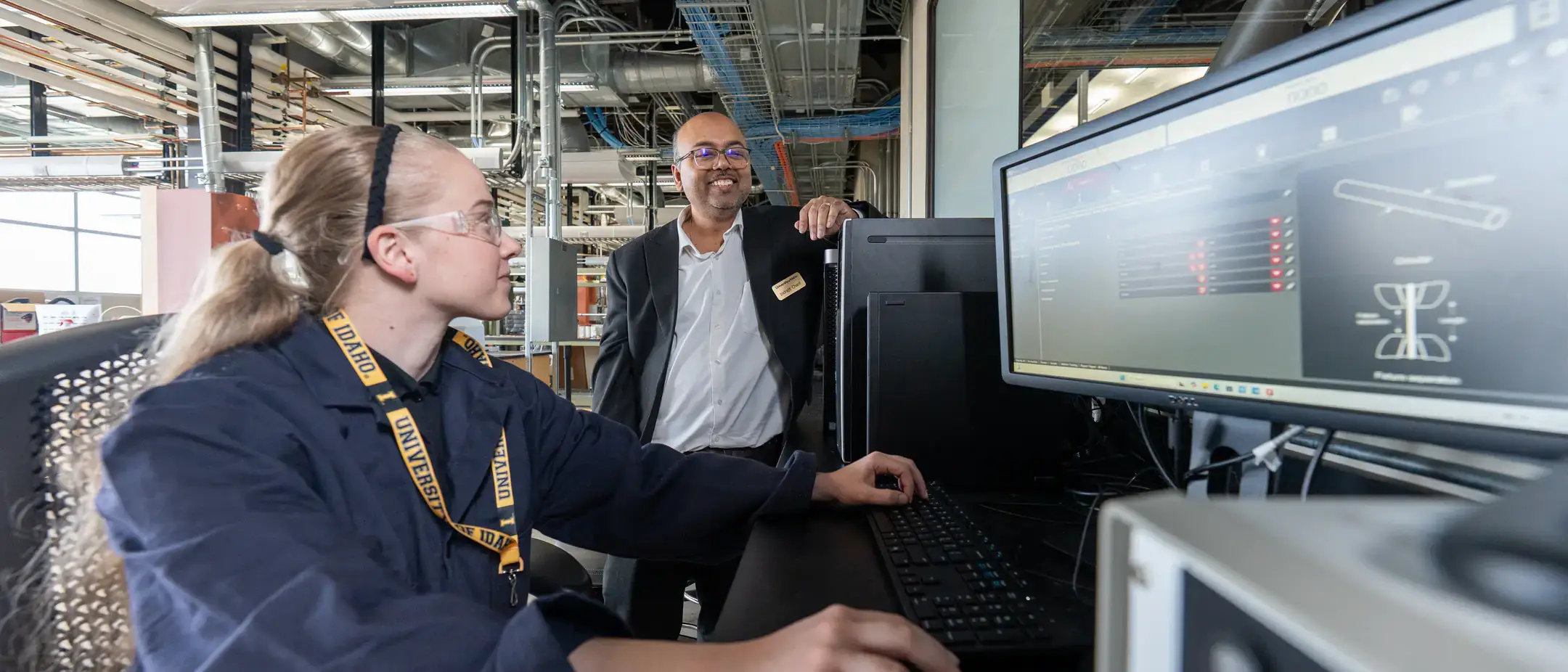 A person engages with scientific software on a monitor in a laboratory, while another individual observes.
