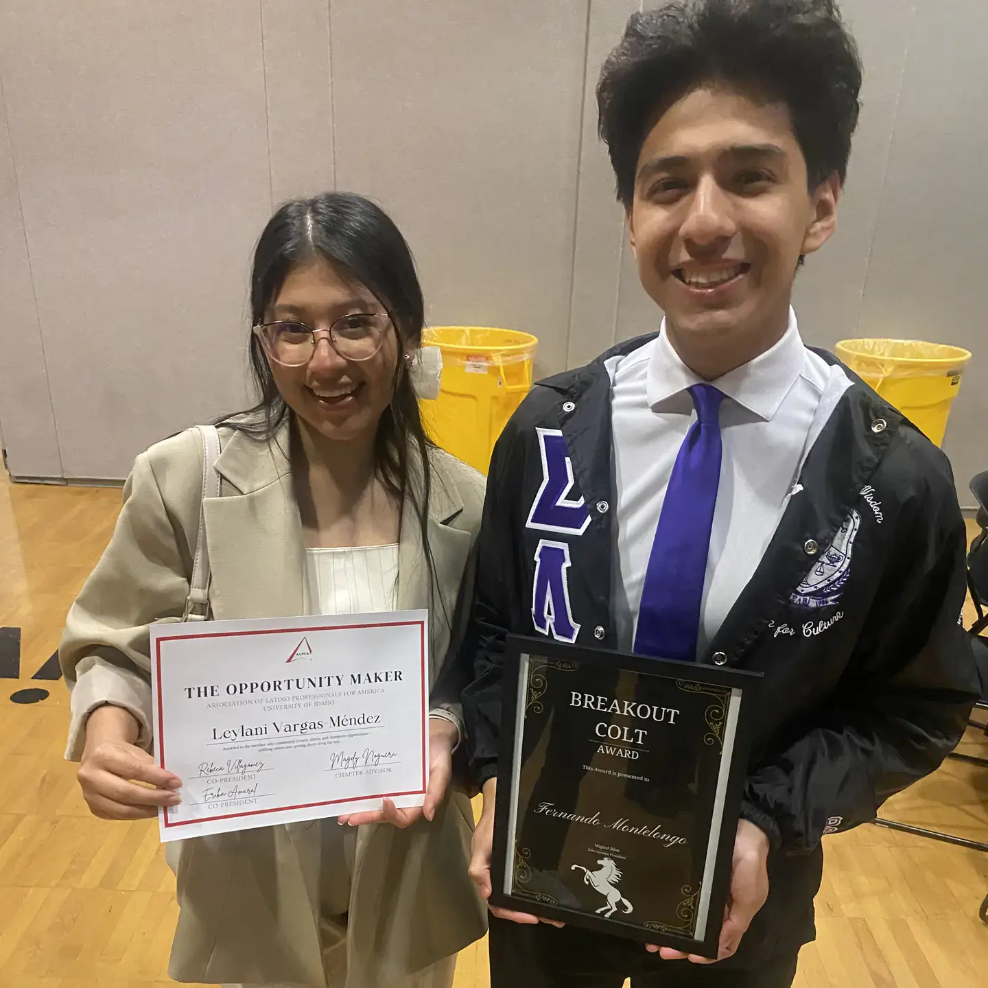 Two students smile while holding an Opportunity Maker certificate and a Breakout Colt Award plaque.