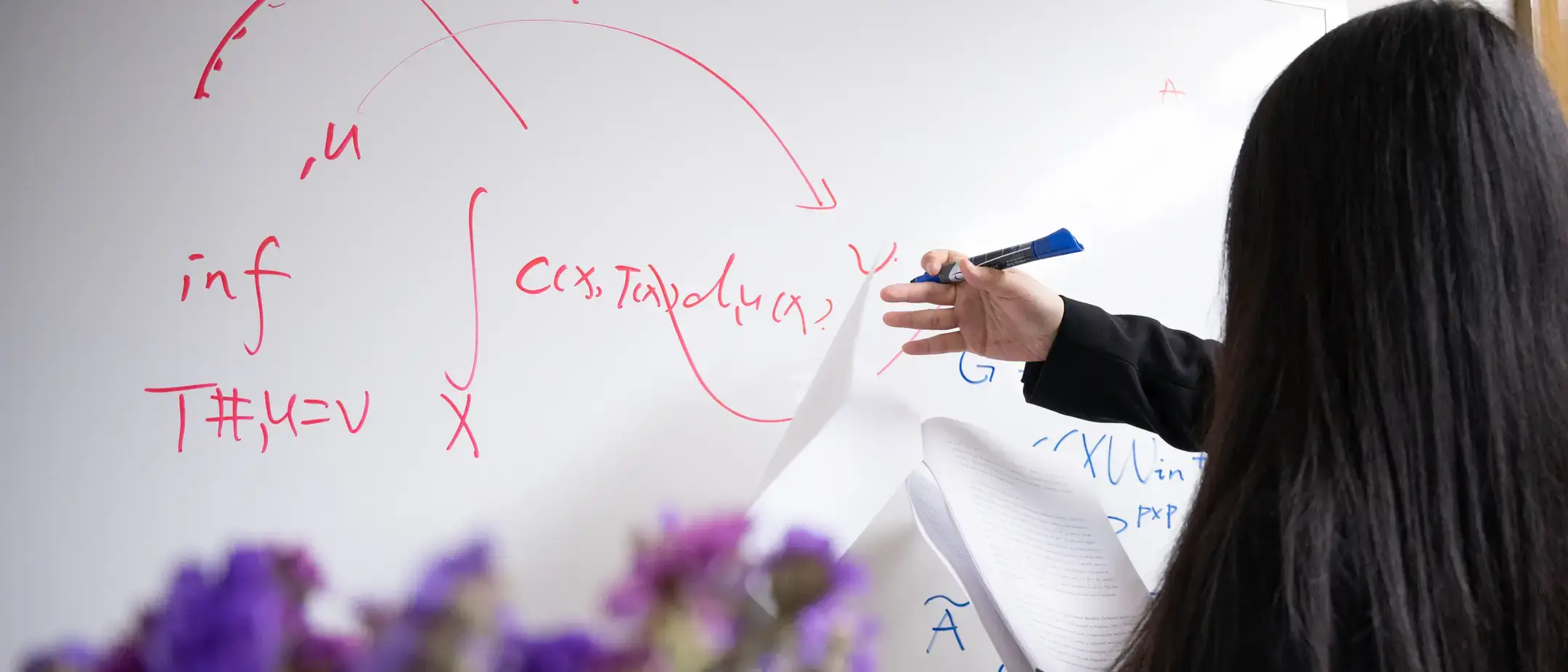 Woman writing math equations on a whiteboard.