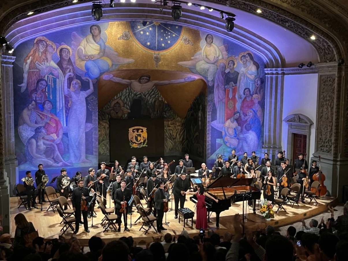 An orchestral stage and mural during a concert featuring Manuel Ponce in Mexico City.