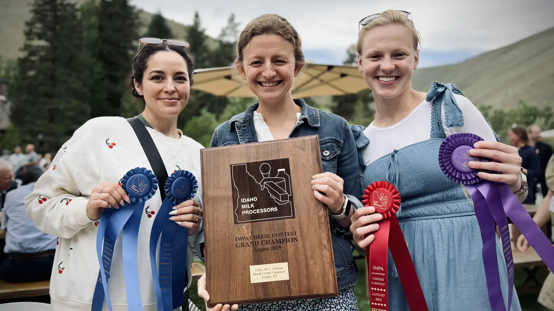 Three women pose together, holding awards.