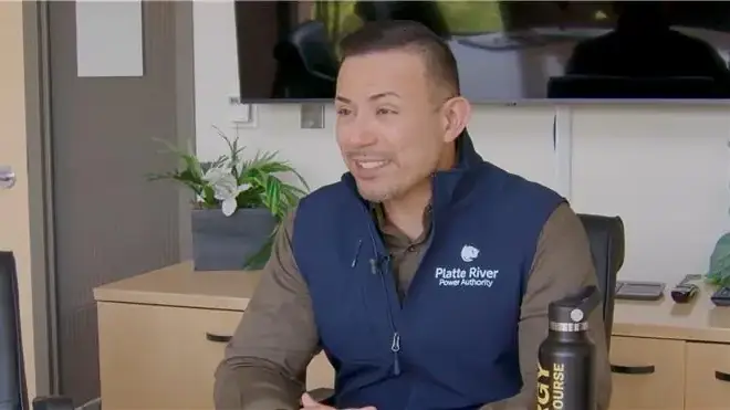 A man in a vest sitting at a desk.