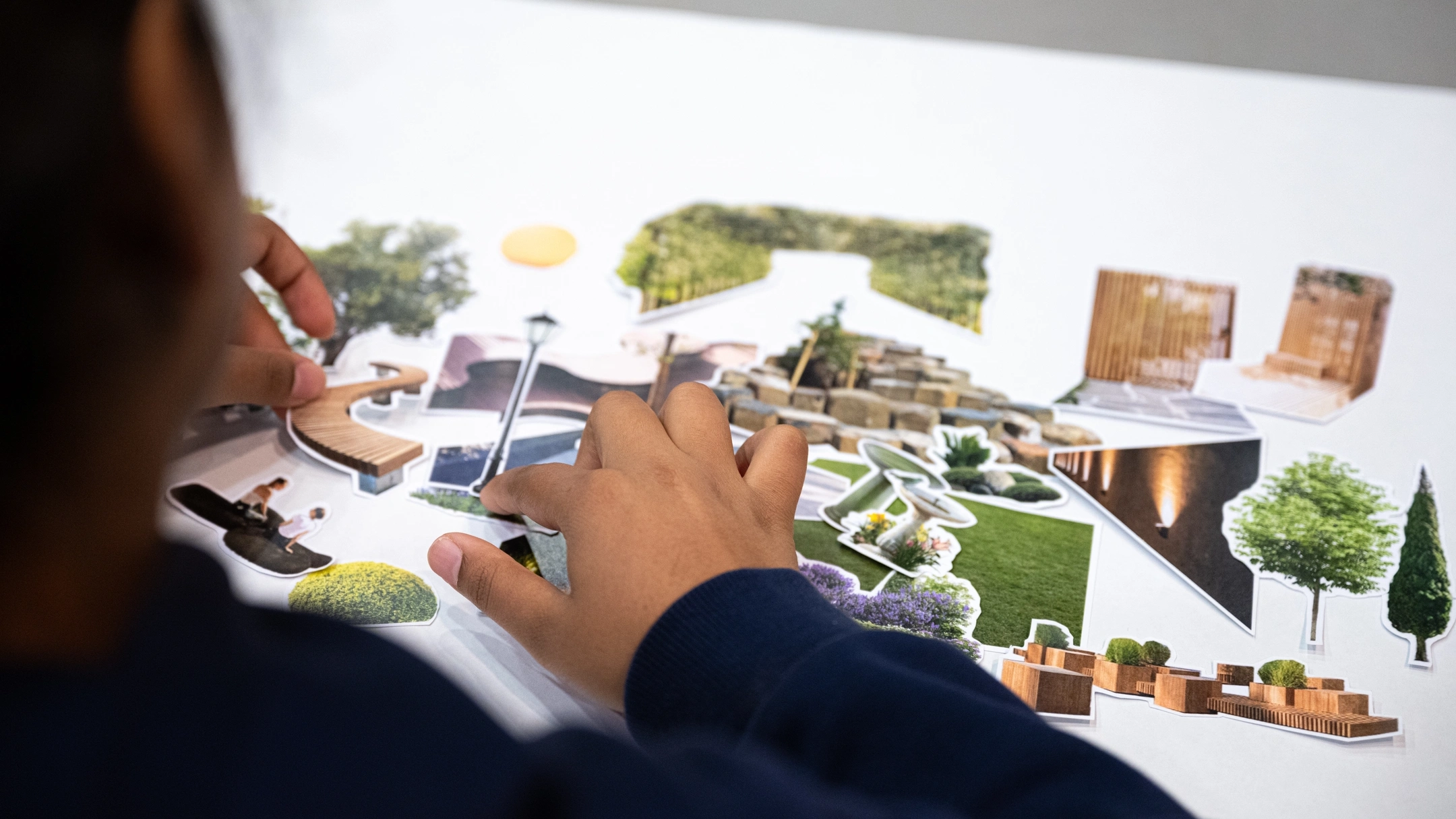 Person using paper cutouts to build a collage.