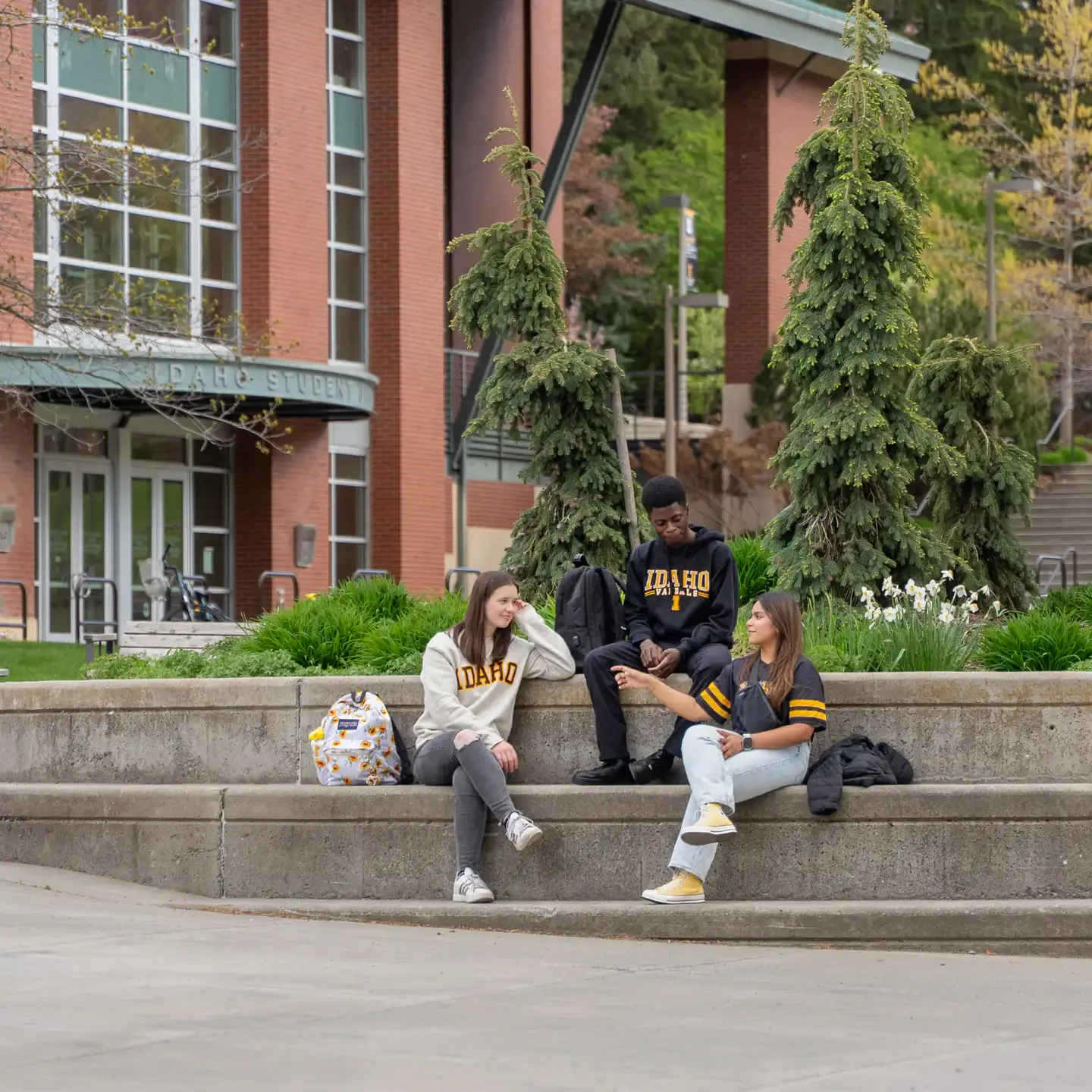Students sitting on a campus step talking.