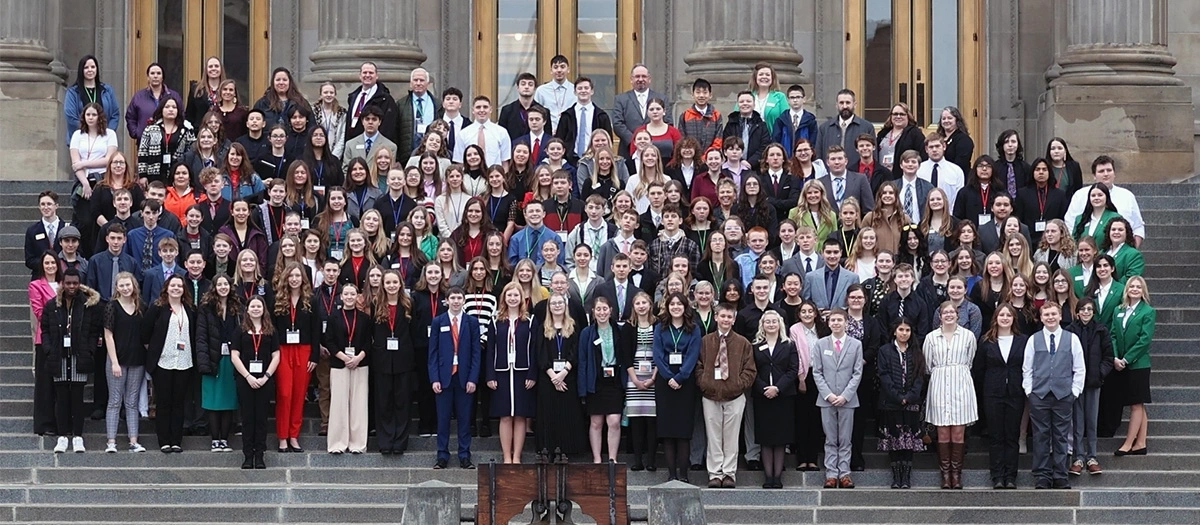 A group of students and government officials on the steps in front of the Boise capitol building