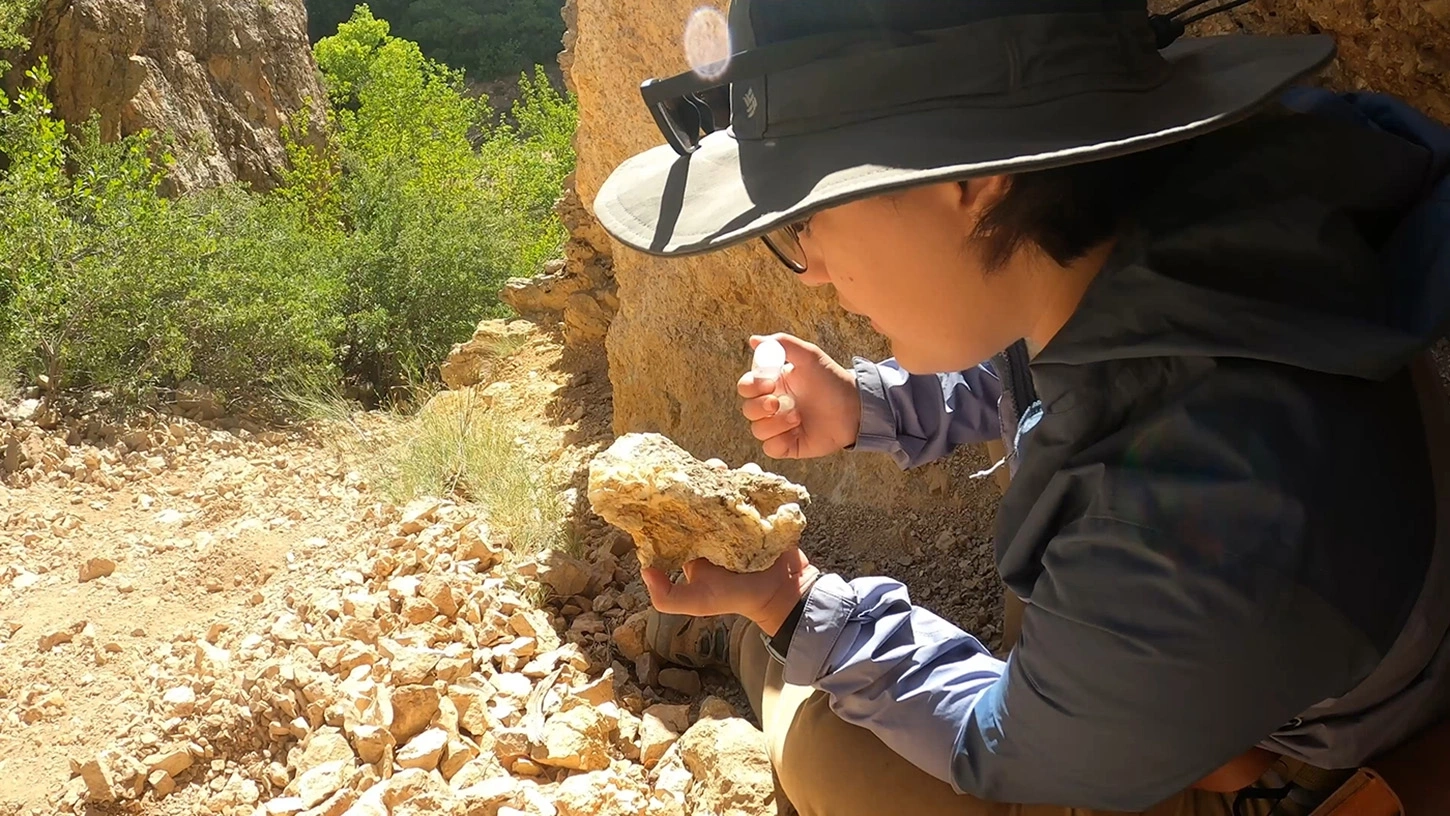 A student examines a rock chunk while outdoors.