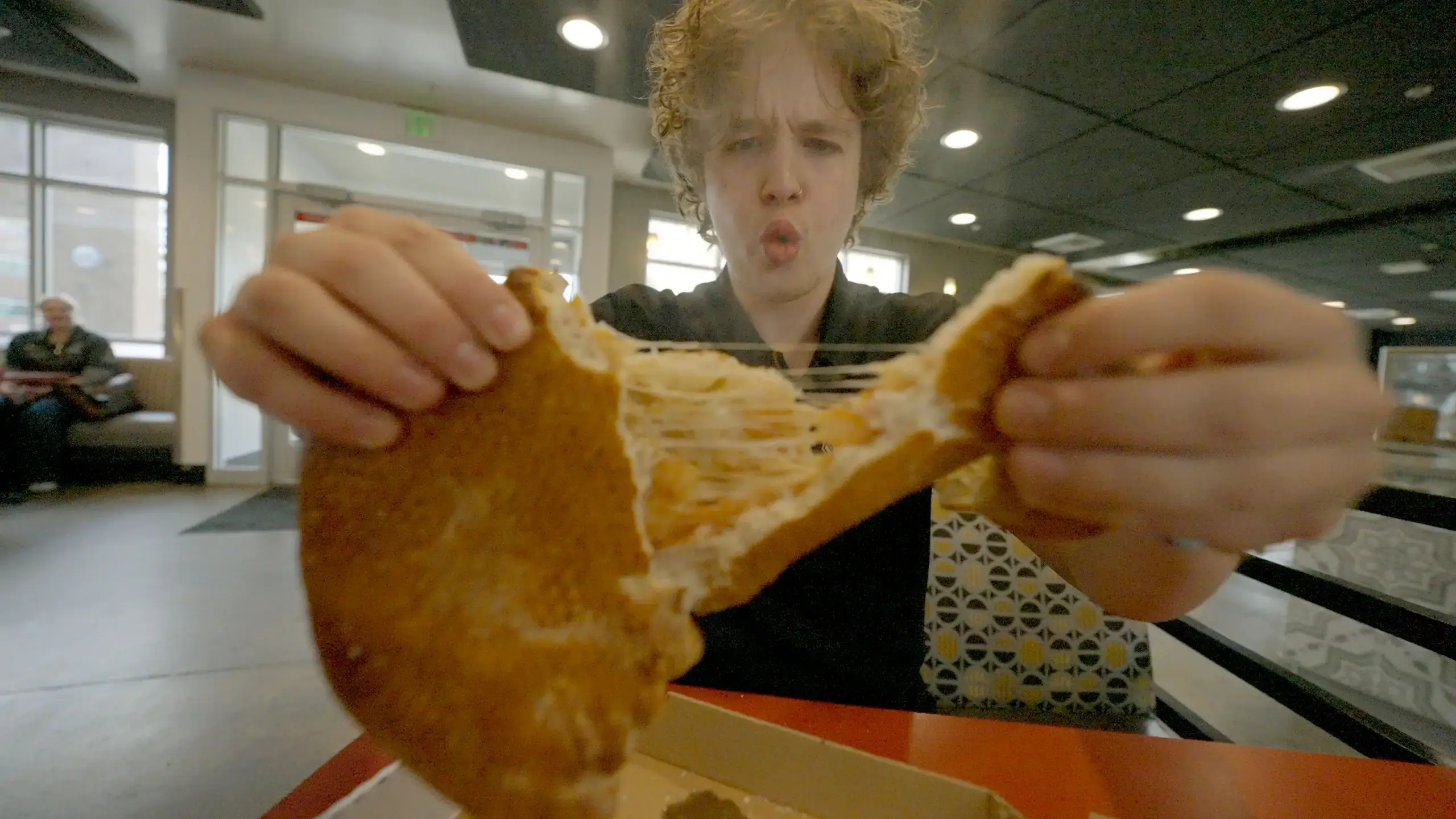 A student tears into a grilled cheese sandwich, unleashing steam. 