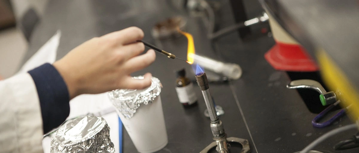 Female hands lighting something in a lab setting.